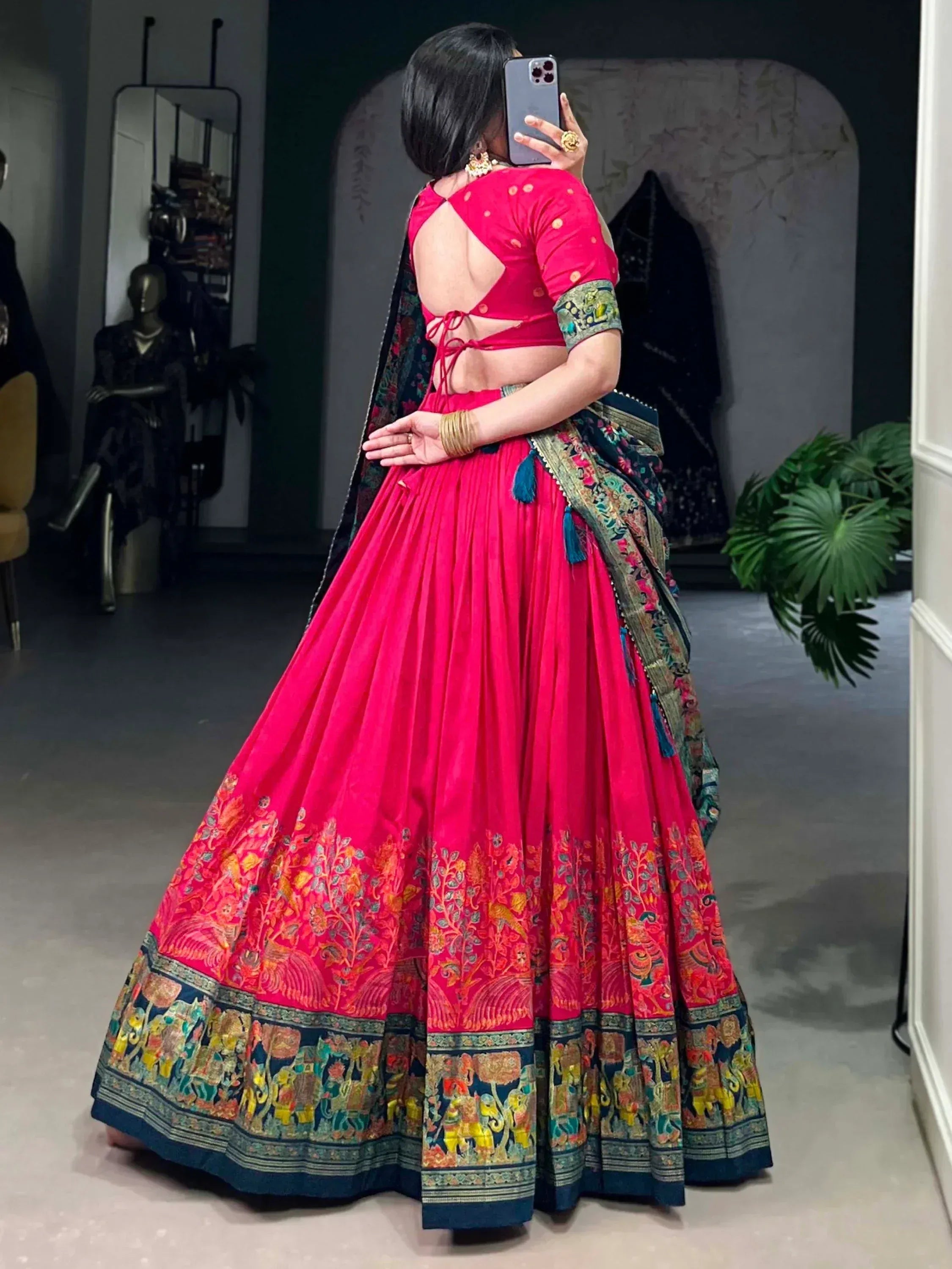 Vibrant pink lehenga choli with floral and elephant border, backless blouse, and embroidered dupatta for Indian ethnic wear.