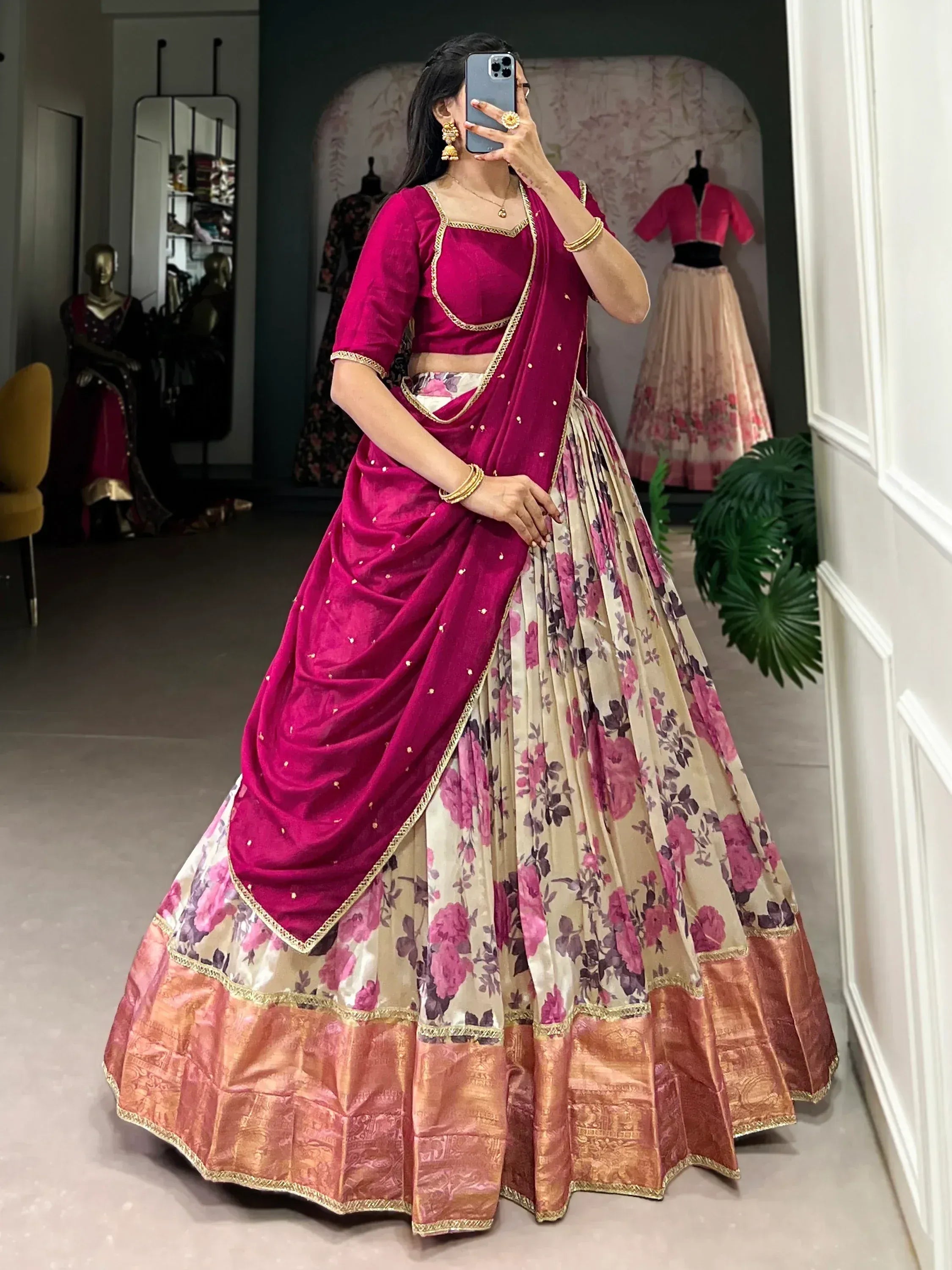 Woman in pink velvet lehenga choli with floral skirt, gold trim, and mirror selfie in boutique