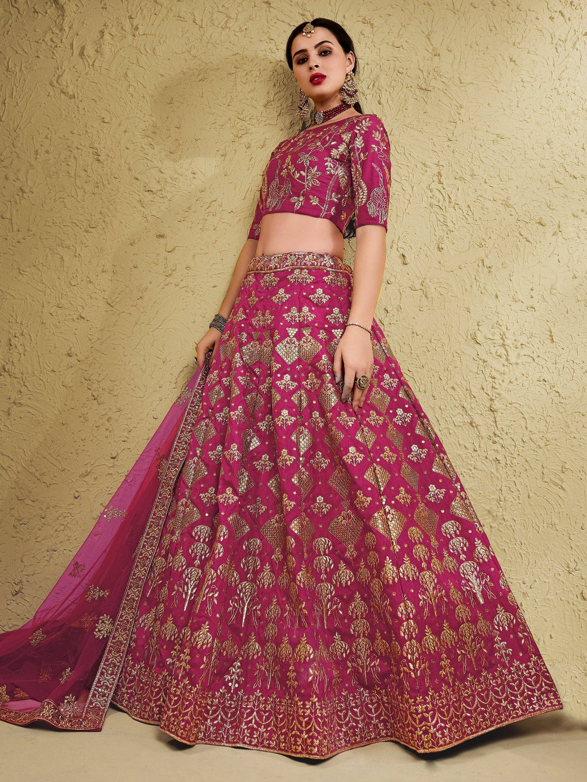 Elegant magenta lehenga choli with gold embroidery, perfect for Indian weddings and festive occasions.