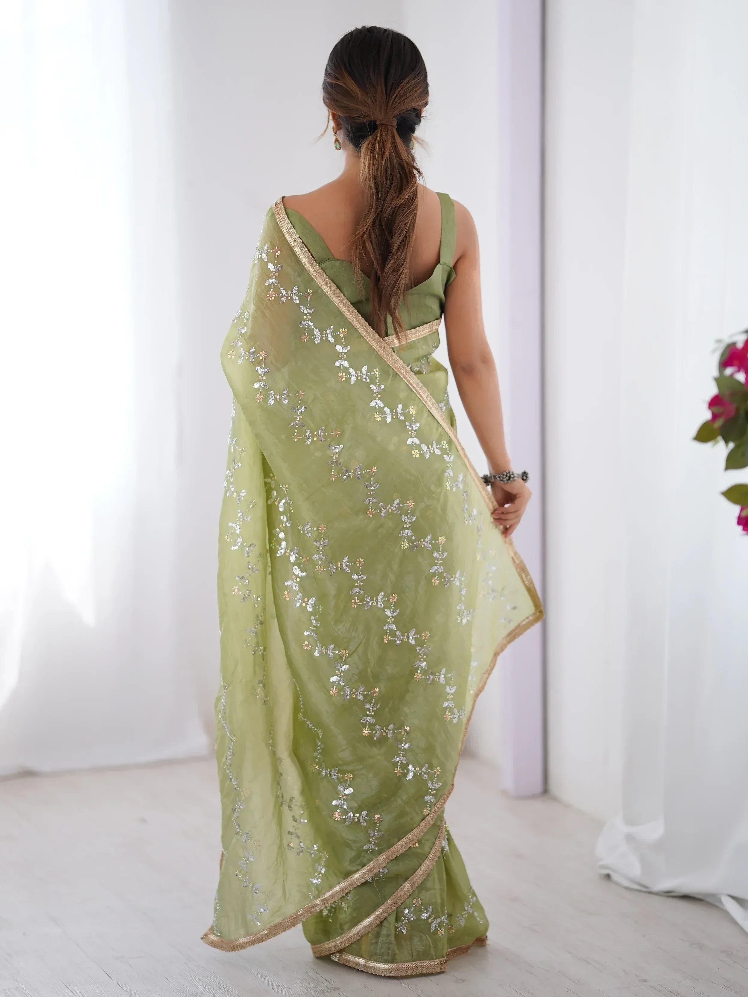 Back view of woman in olive green embroidered saree with gold border, Indian ethnic wear