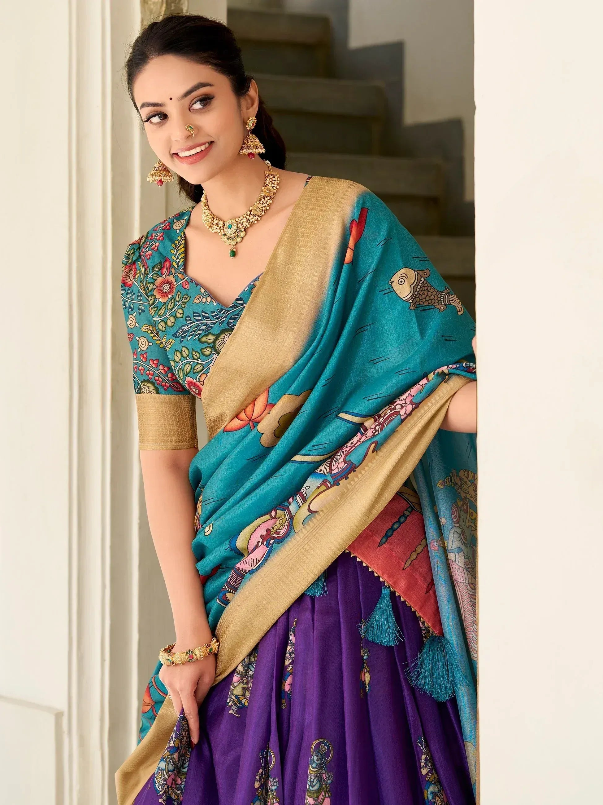 Woman in teal printed saree with gold border and purple lehenga, traditional Indian ethnic wear