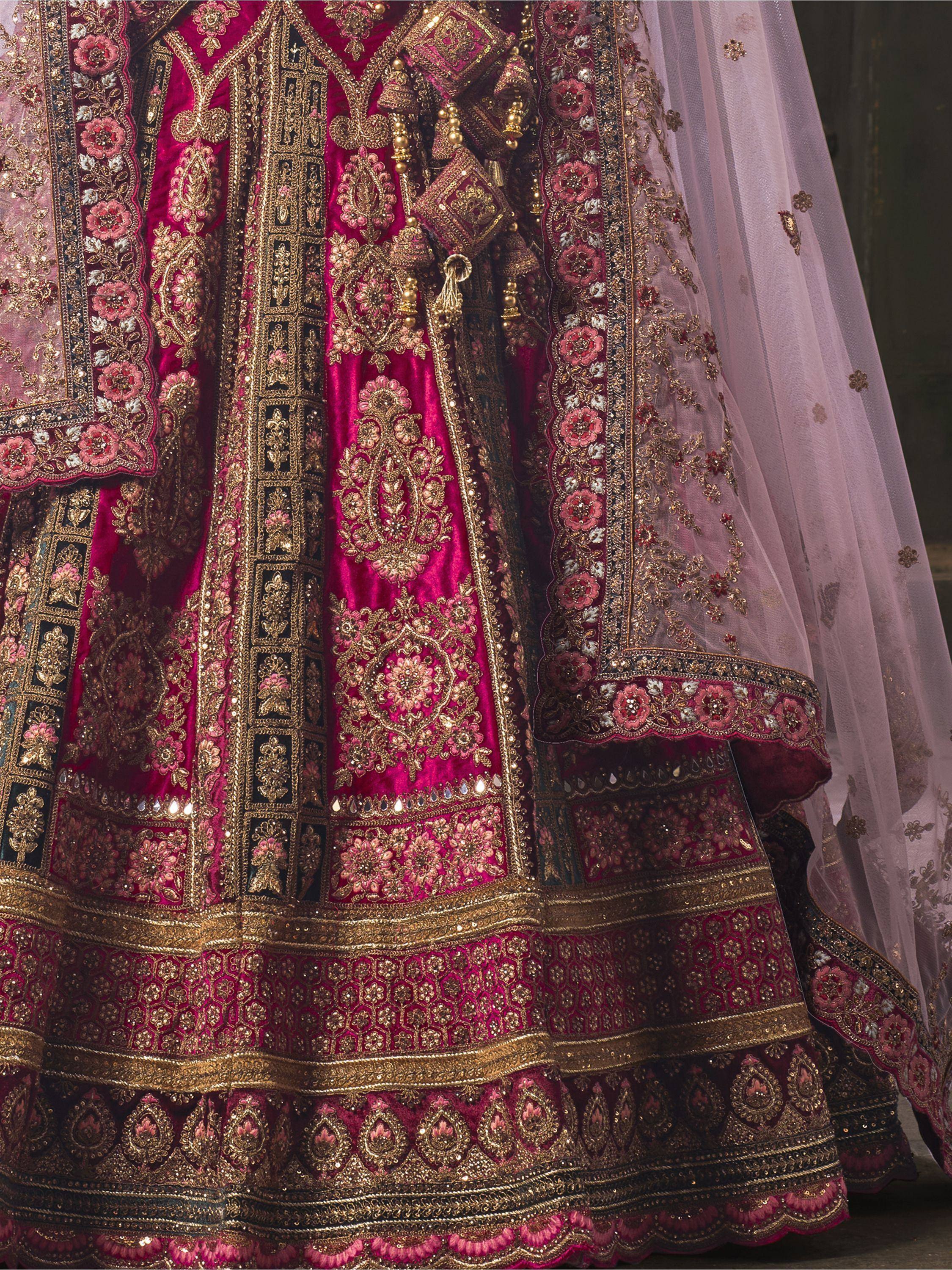 Luxury pink velvet lehenga choli with heavy gold embroidery and floral motifs, perfect for Indian weddings.