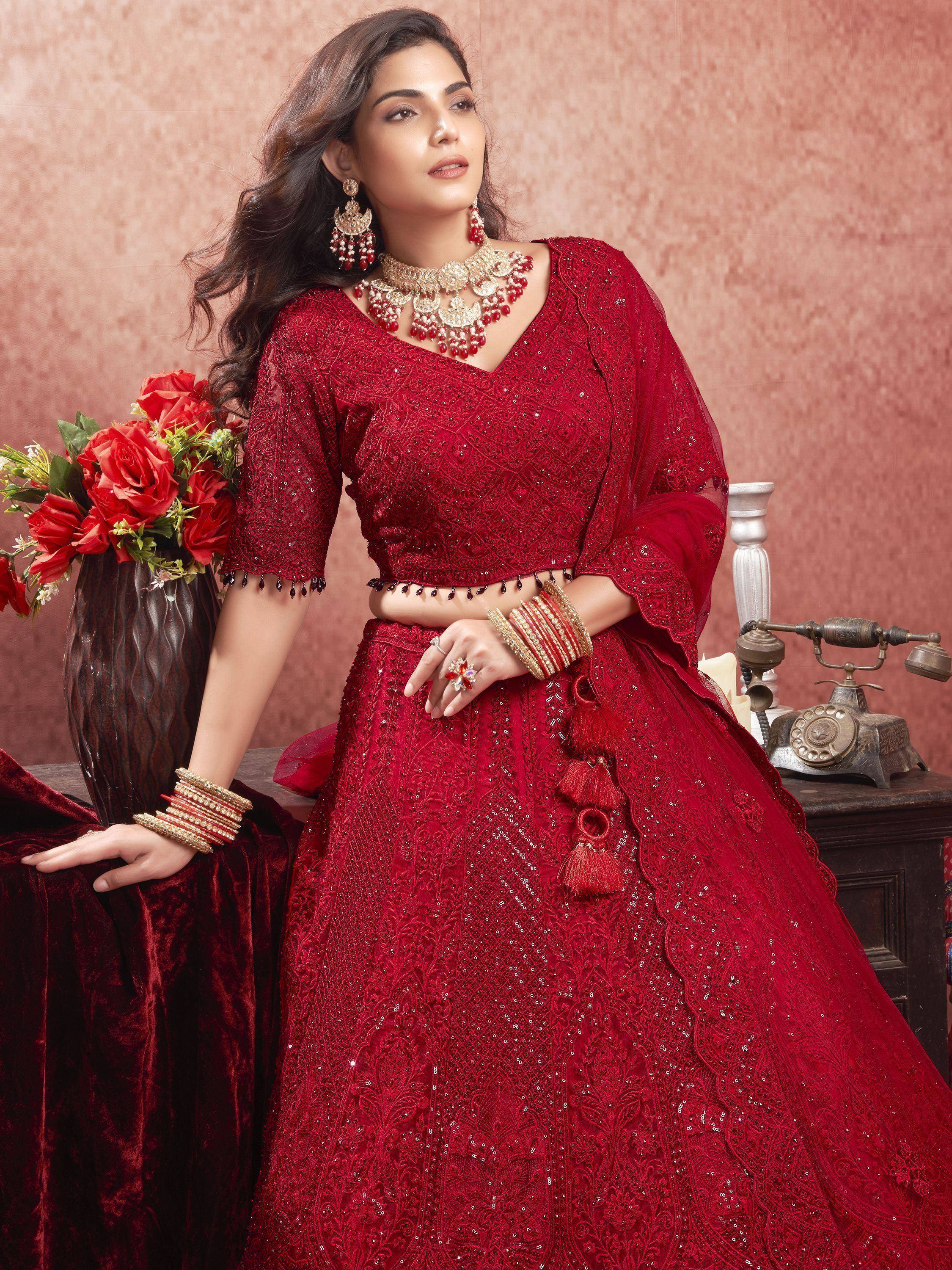 Red embroidered lehenga choli with sequins, tassels, and traditional jewelry for Indian ethnic wear