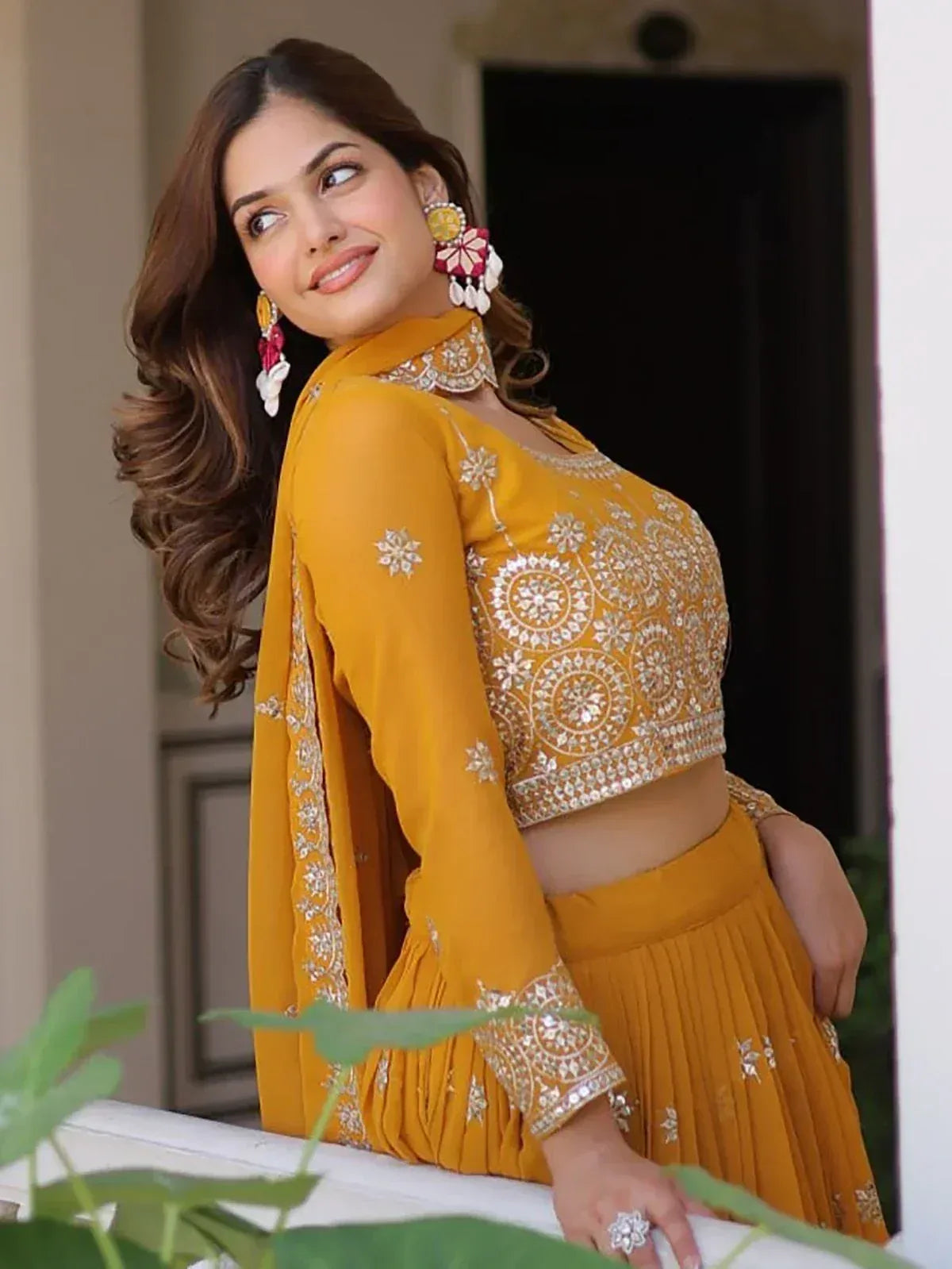 Yellow embroidered lehenga choli with mirror work, floral earrings, perfect for Indian ethnic occasions