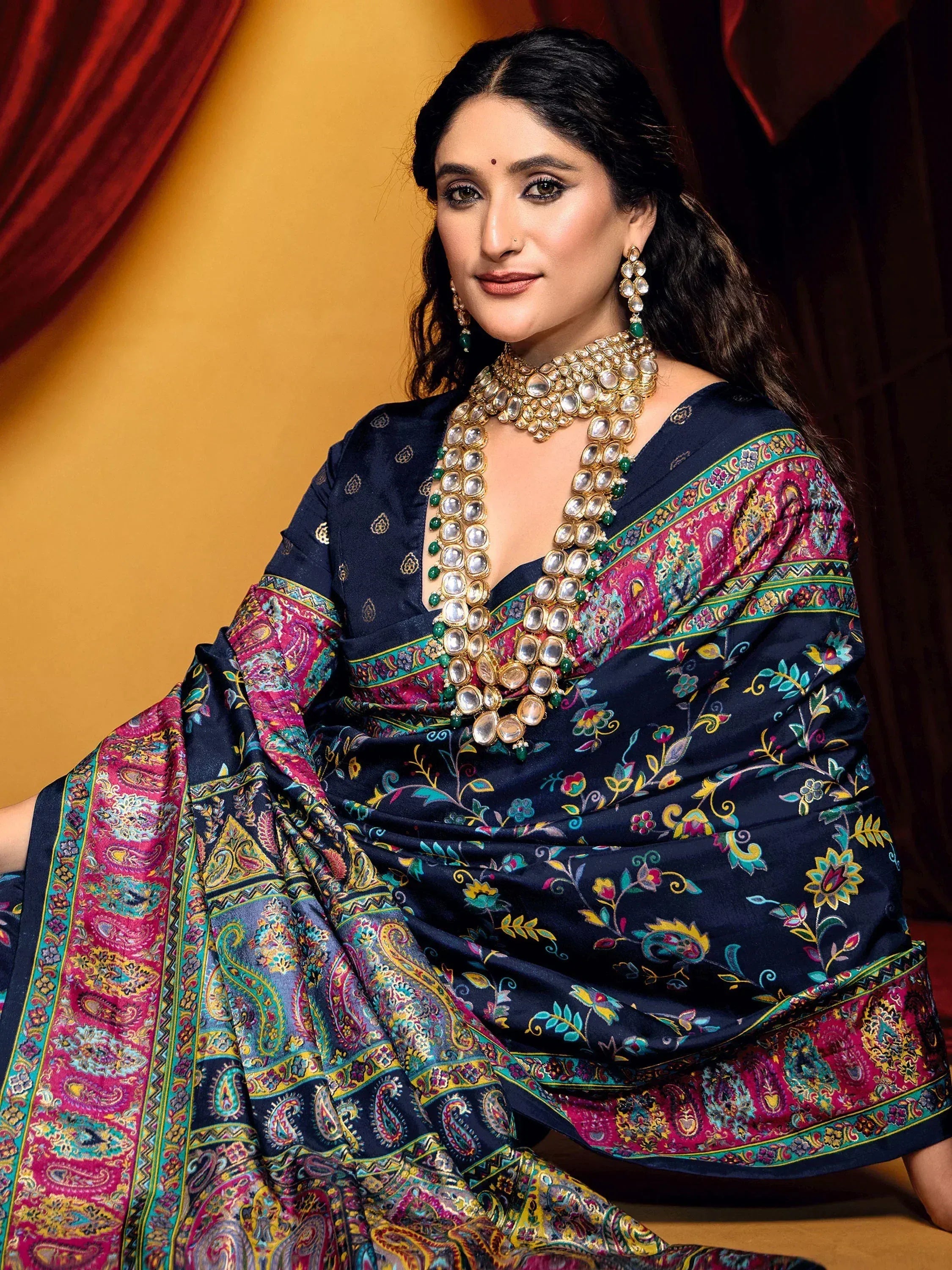 Woman in navy blue floral saree with vibrant paisley border, paired with traditional Indian jewelry