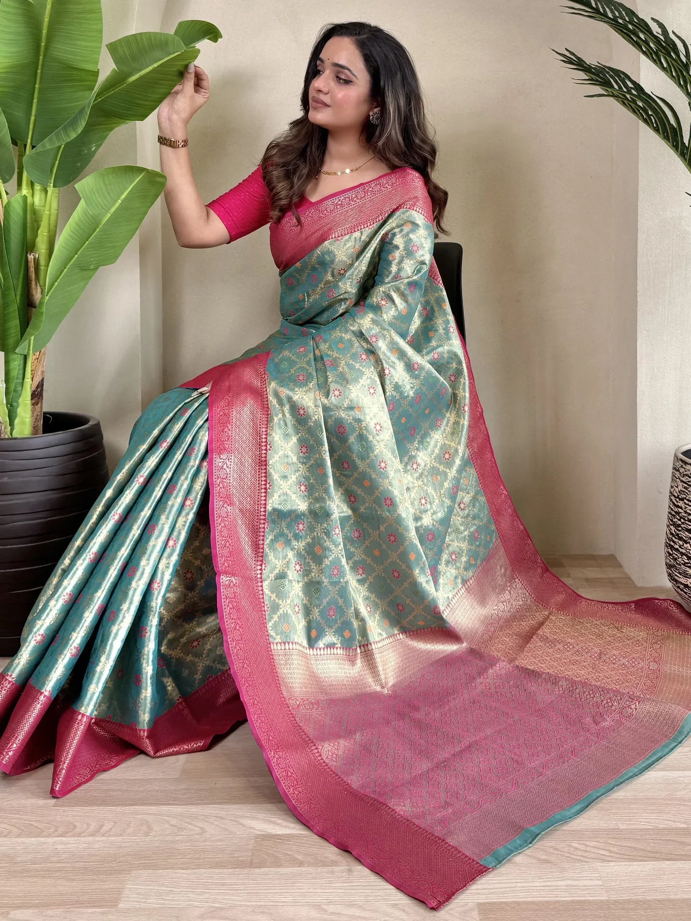 Woman in teal and pink designer saree with floral motifs, perfect for Indian ethnic wear occasions.