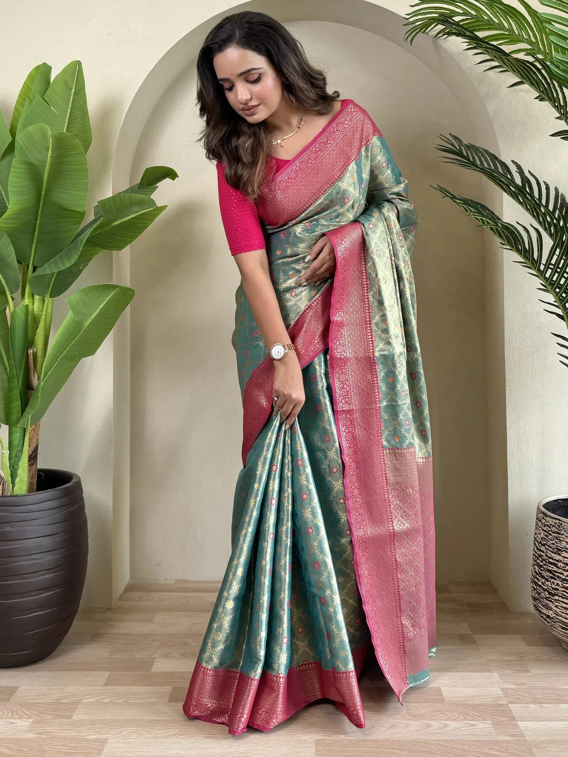 Teal and pink designer saree with gold floral motifs and intricate border, paired with matching blouse
