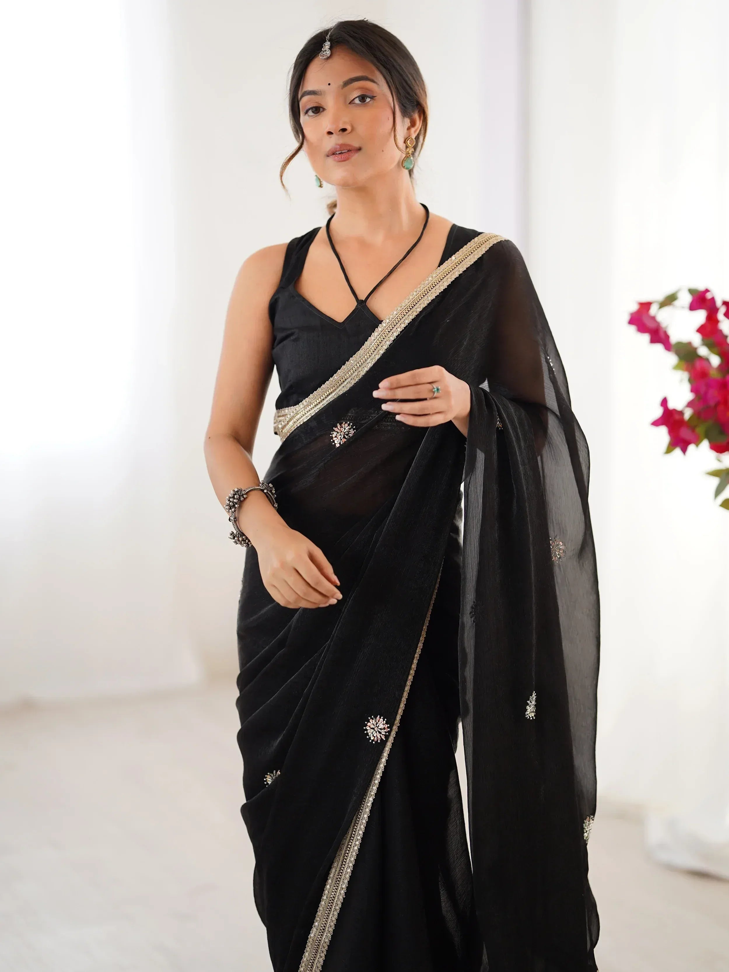 Black saree with gold border and floral embroidery, styled with ethnic jewelry for Indian occasions