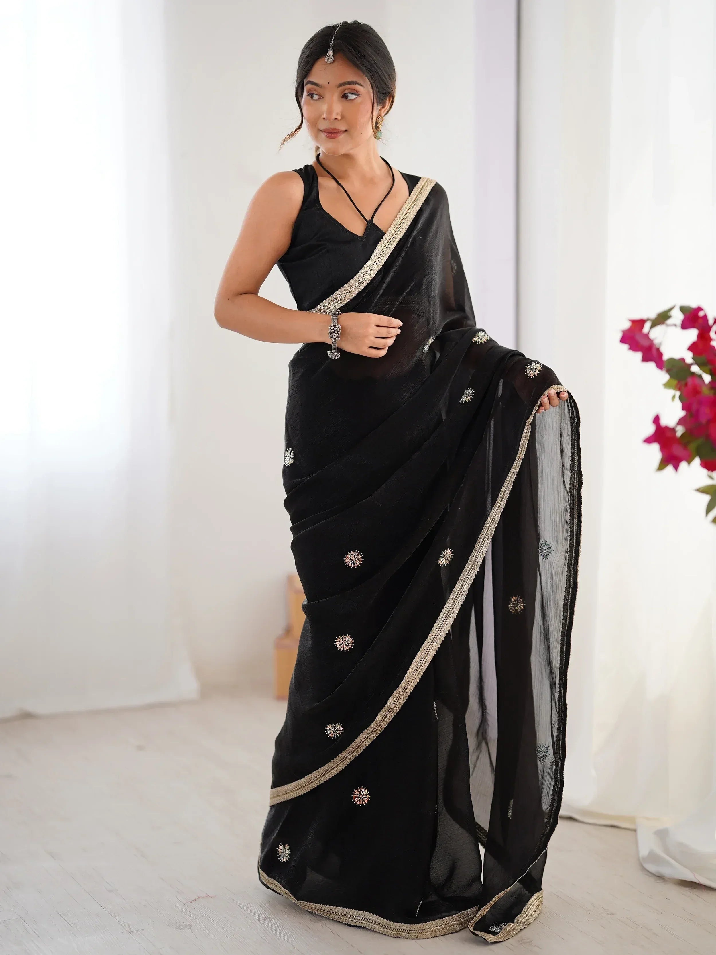 Black embroidered saree with gold border, styled with sleeveless blouse for ethnic wear