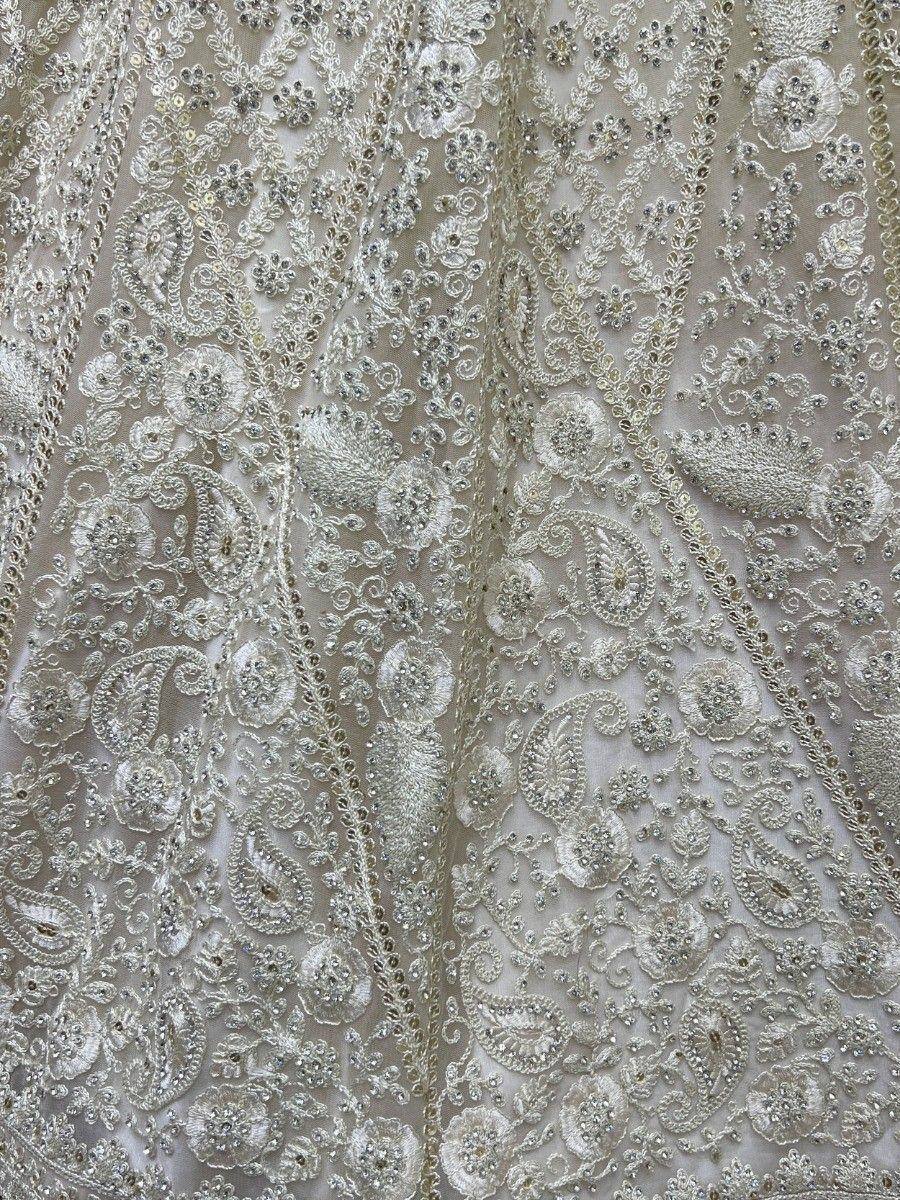 Intricate silver embroidery with floral and paisley motifs on sheer ethnic fabric, perfect for designer lehenga or saree.