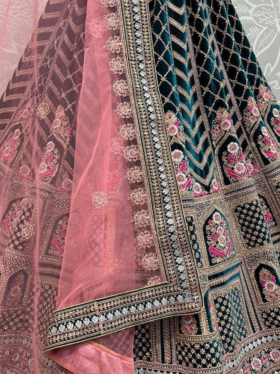 Designer lehenga choli with intricate embroidery, velvet fabric, and floral motifs in teal and pink