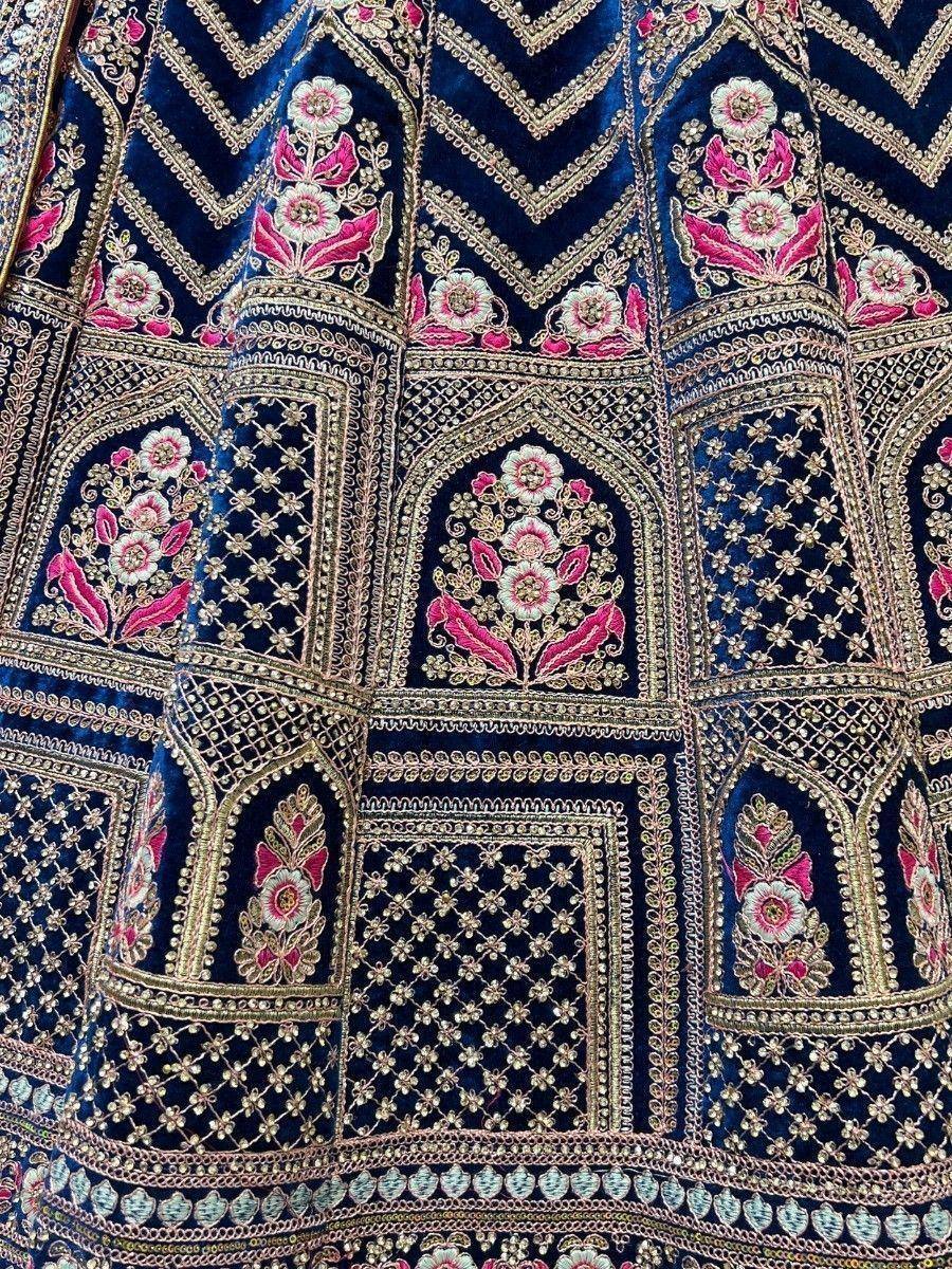 Luxury navy blue velvet lehenga with intricate gold and pink floral embroidery, perfect for Indian weddings and festive occasions.