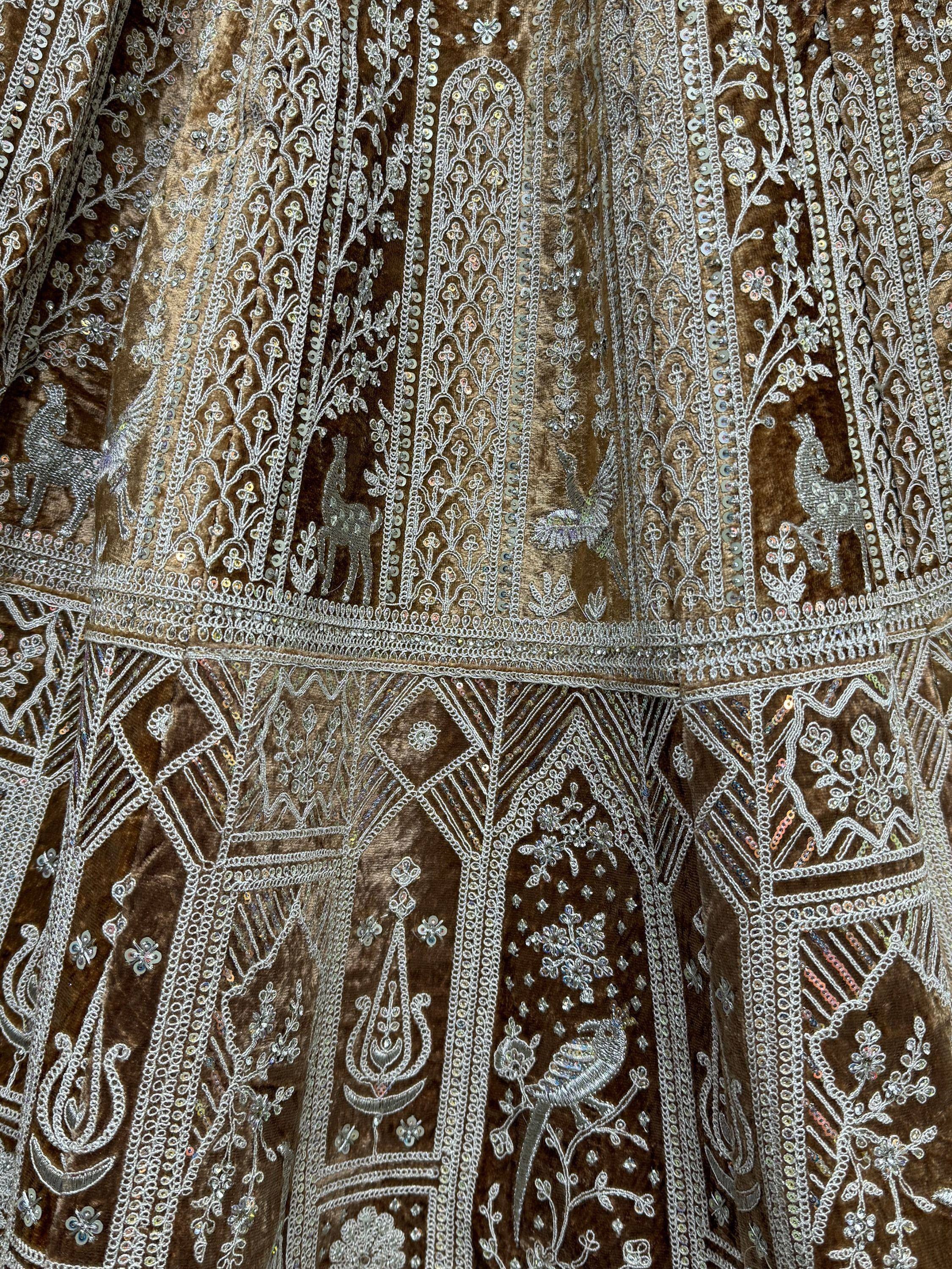 Brown velvet ethnic gown with silver embroidery, sequins, and deer motifs for festive occasions.