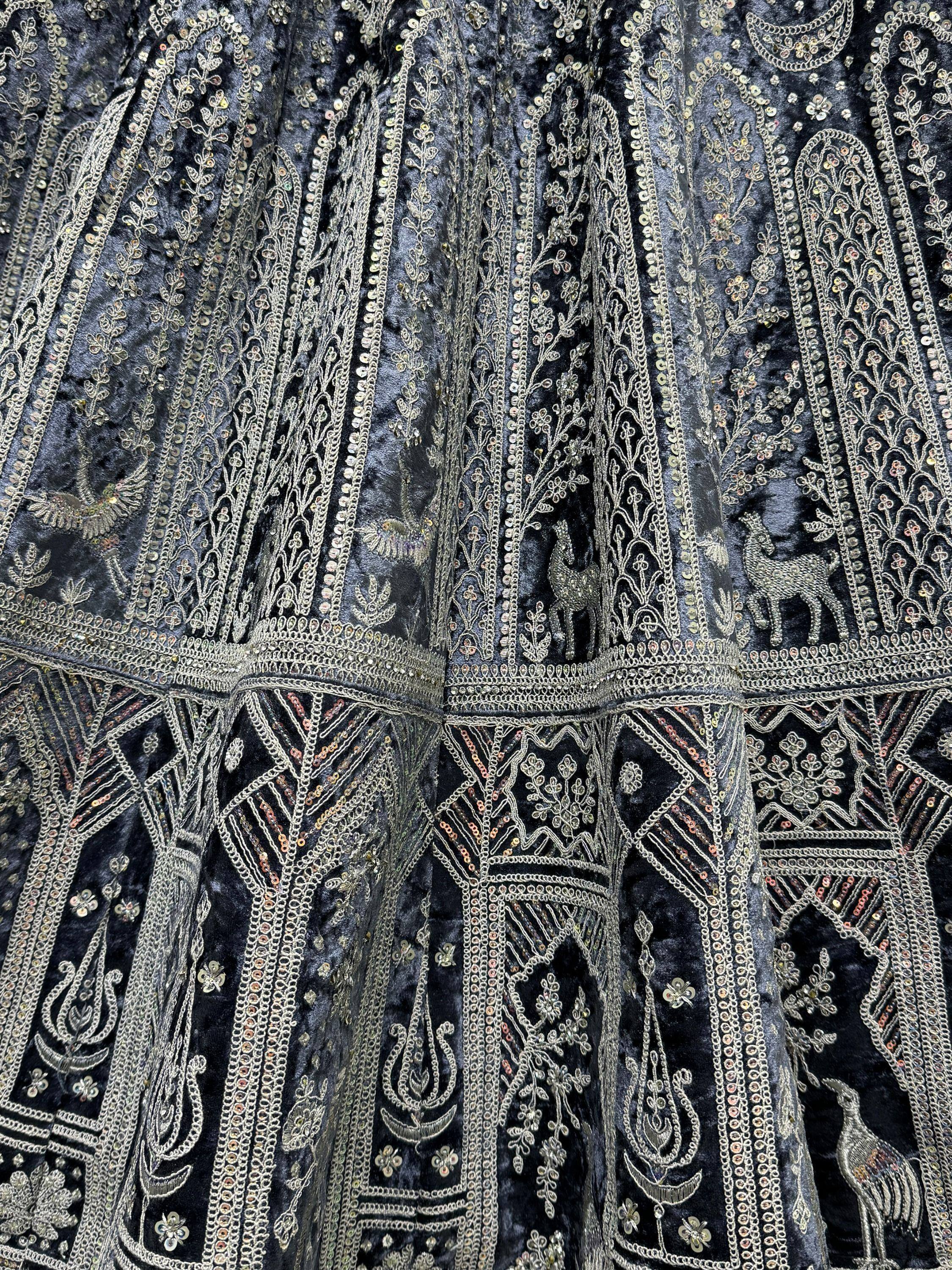 Dark velvet ethnic gown with intricate gold embroidery, sequins, and animal motifs for festive occasions.