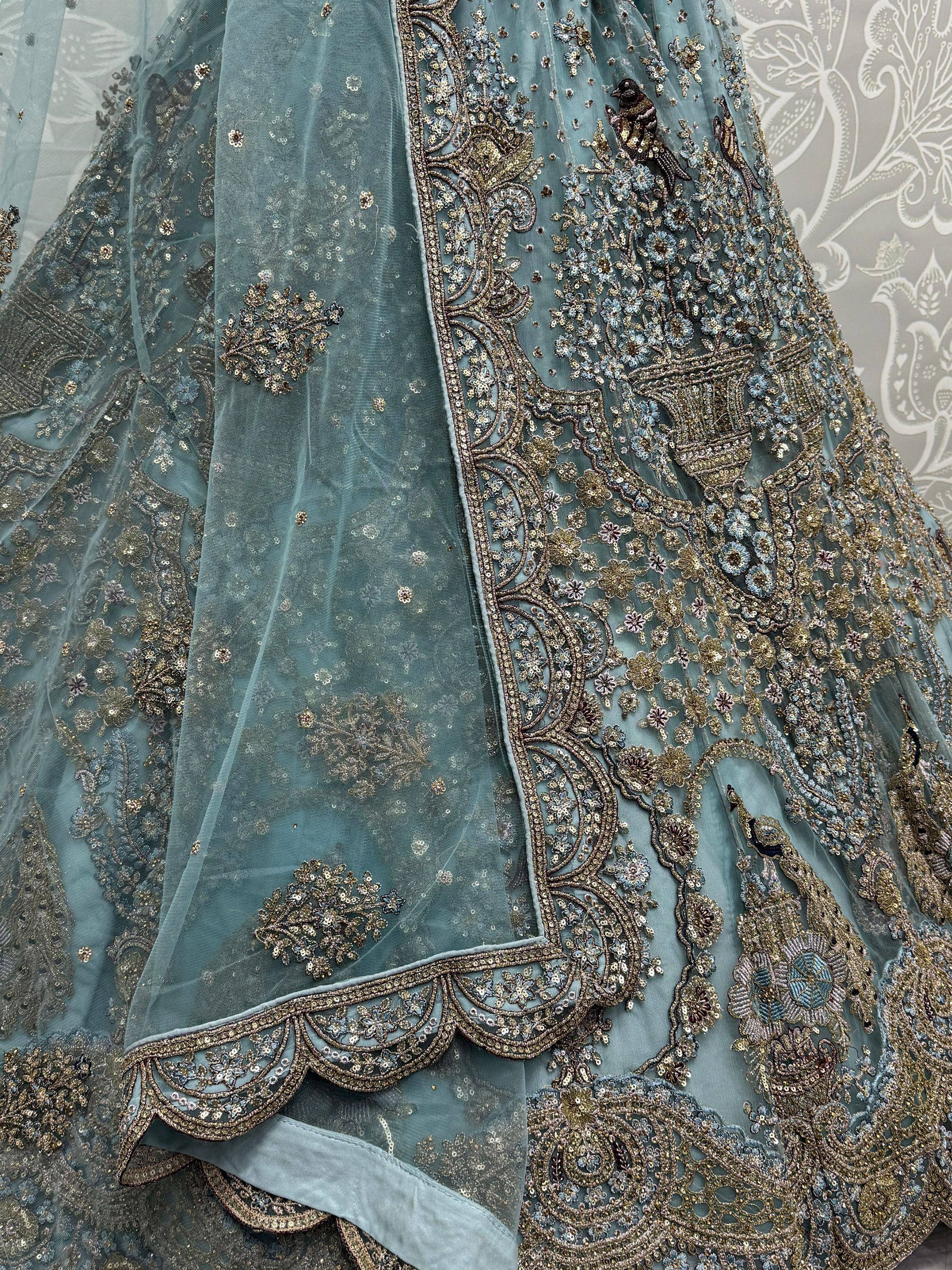 Dusty blue designer lehenga with gold floral and bird embroidery, perfect for Indian weddings or festive occasions.