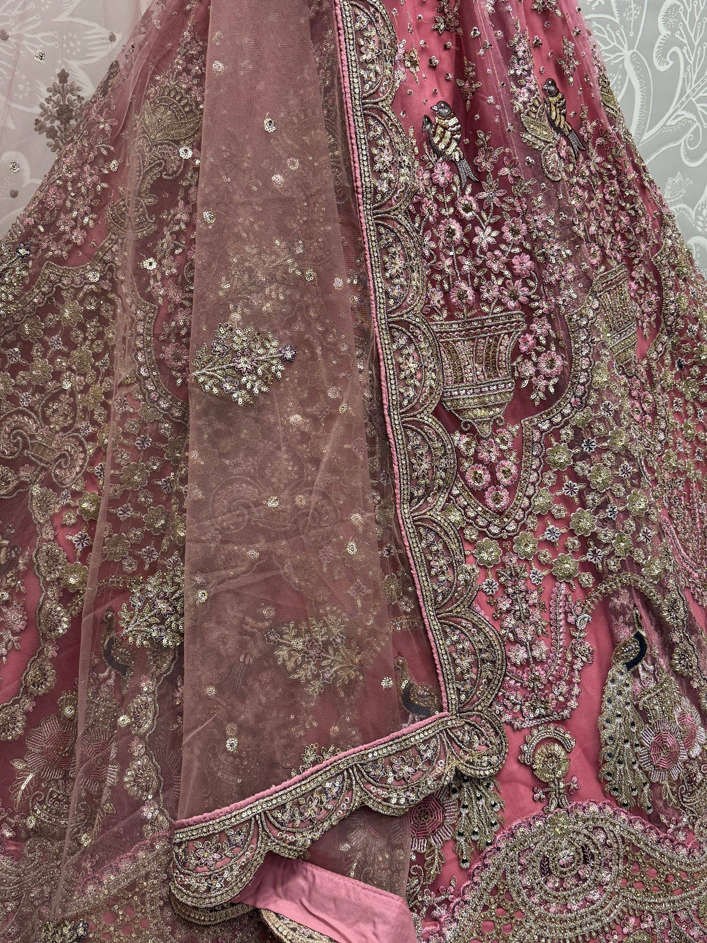 Pink designer lehenga with intricate gold embroidery, floral patterns, and bird motifs for Indian ethnic wear.