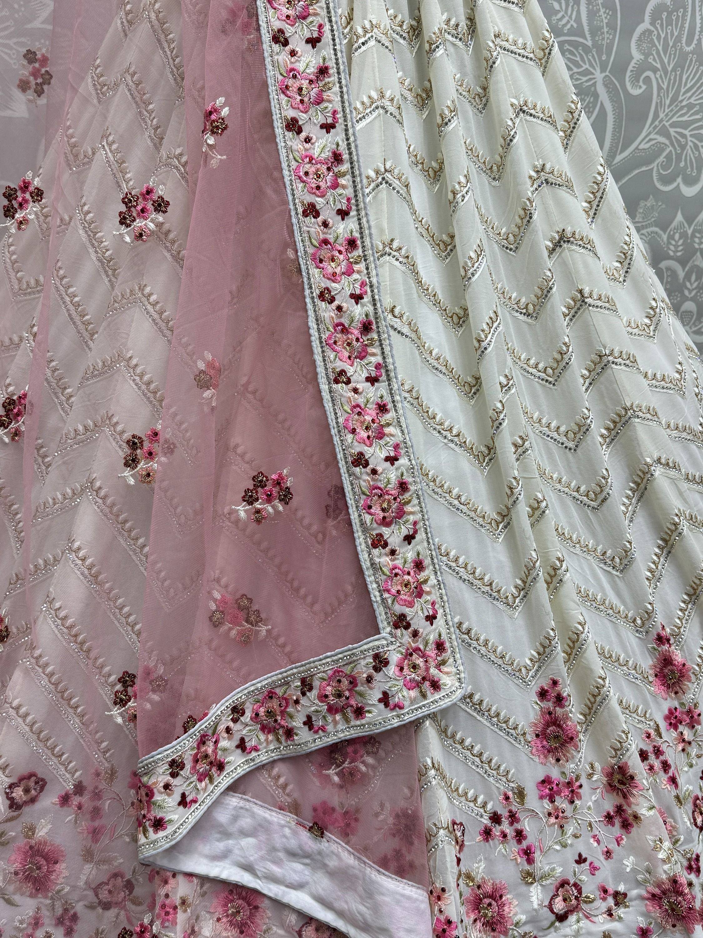 Elegant white and pink embroidered lehenga with floral detailing and zigzag patterns