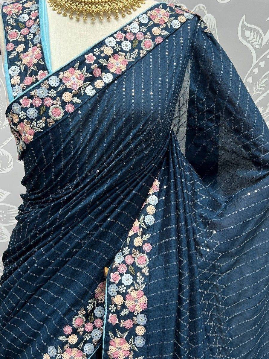 Dark blue saree with floral embroidery and sequin detailing, paired with gold jewelry