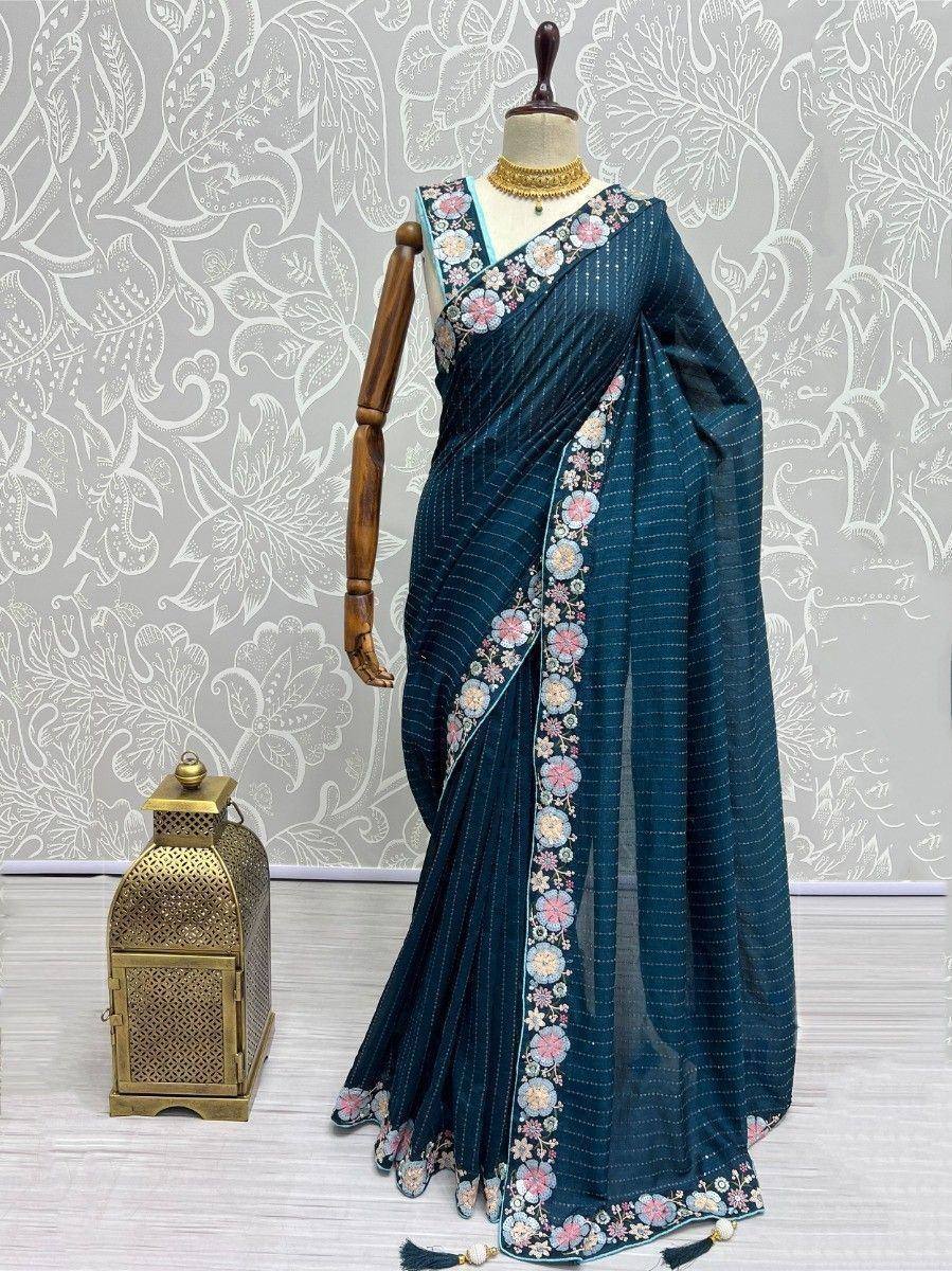 Teal floral embroidered saree with gold jewelry, displayed on mannequin for ethnic wear