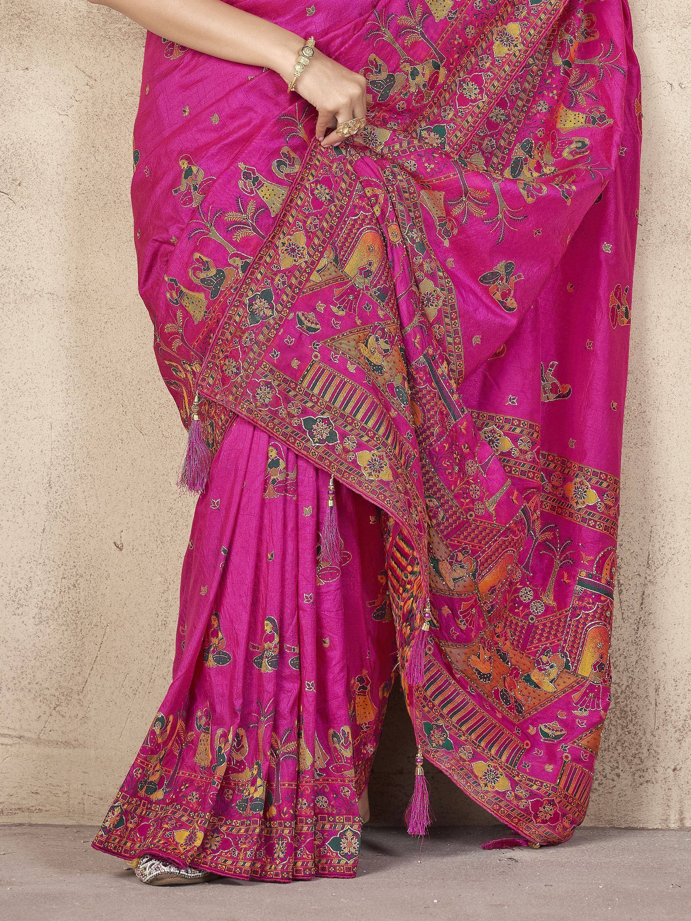 Vibrant pink ethnic saree with intricate gold and green printed motifs, tassels, and traditional Indian design
