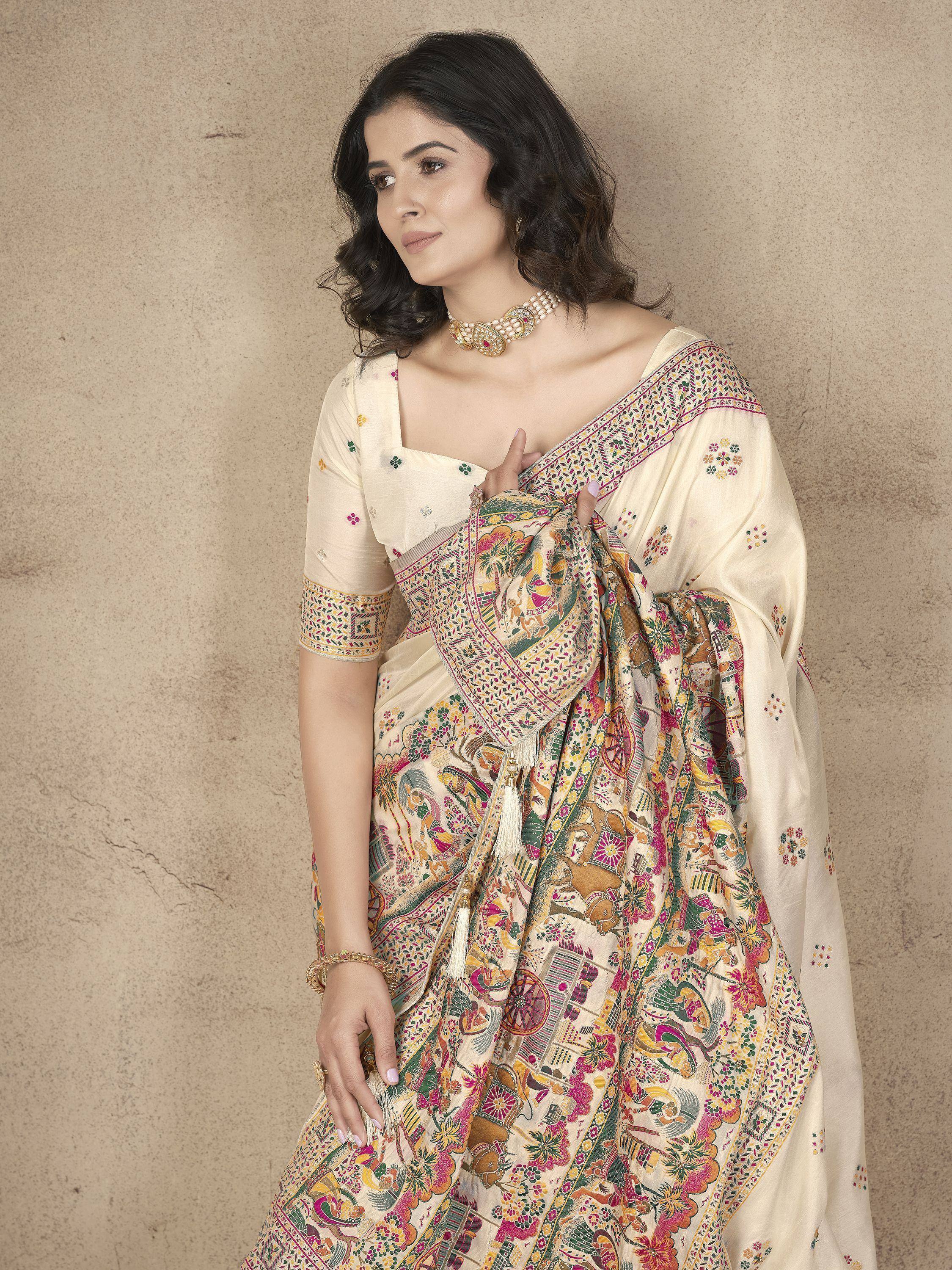 Woman in cream saree with colorful floral and elephant print, paired with embroidered blouse and gold jewelry