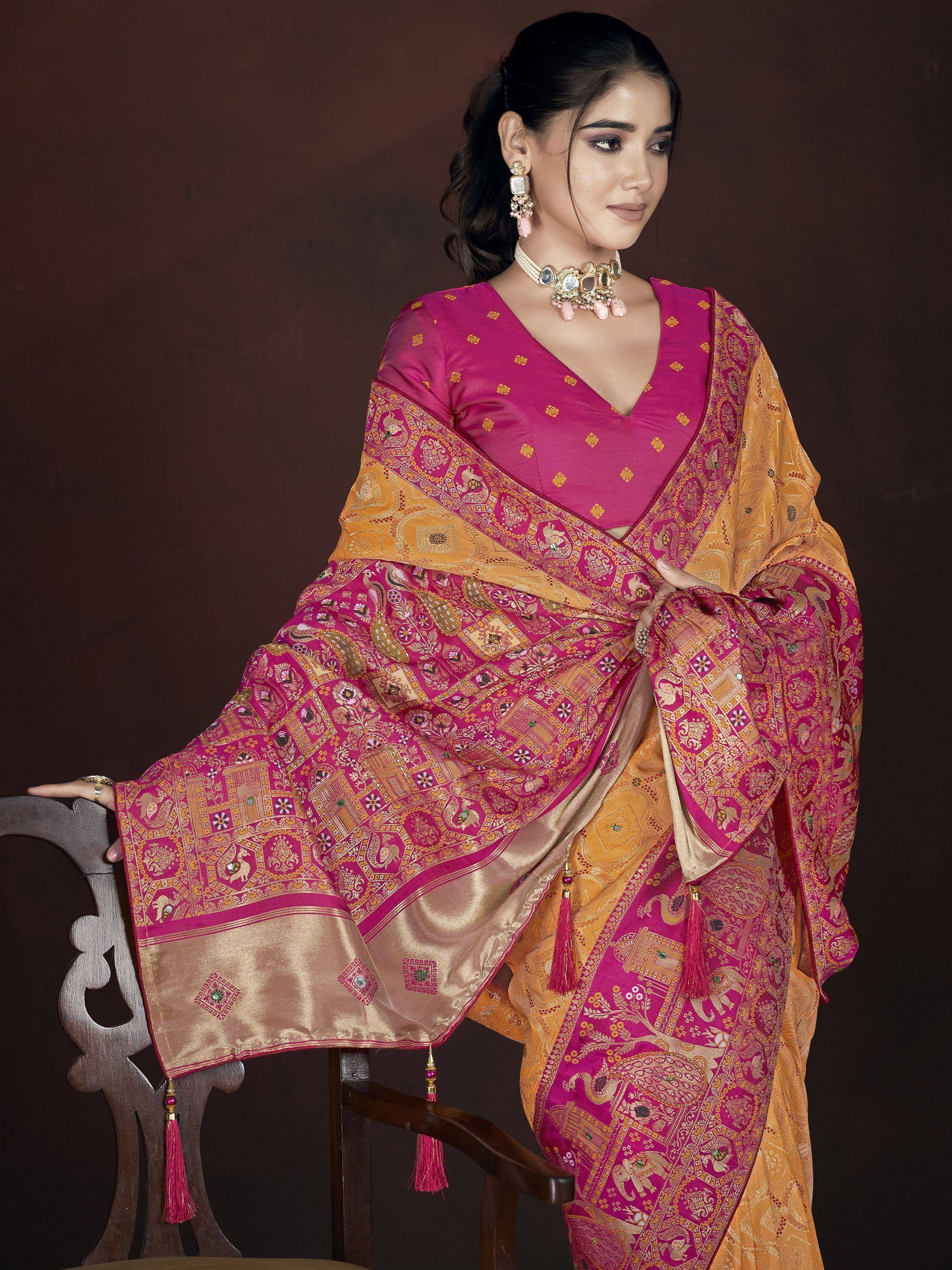 Woman in vibrant pink and gold ethnic saree with intricate patterns and tassels, styled with traditional jewelry.