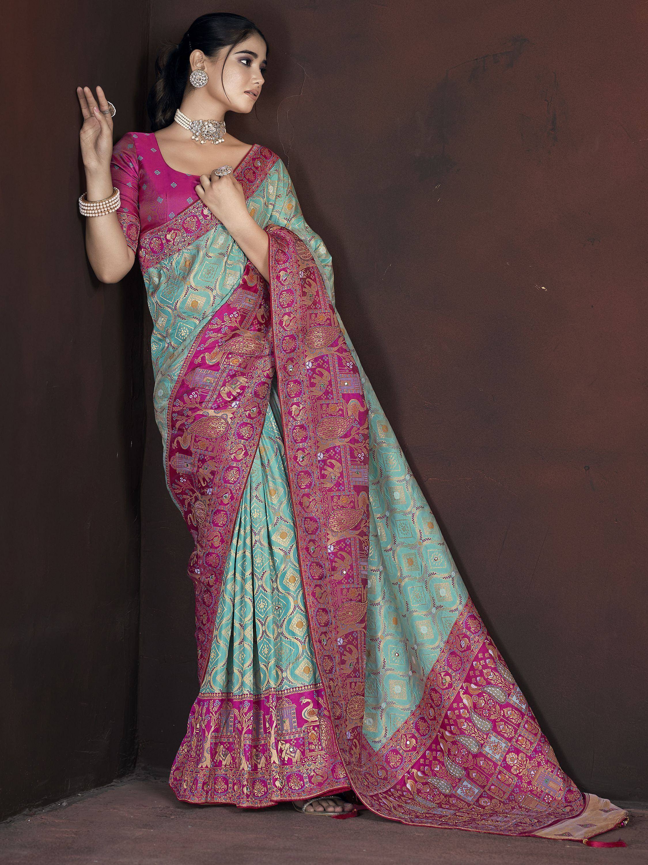 Woman in turquoise and magenta designer saree with intricate gold embroidery and traditional jewelry