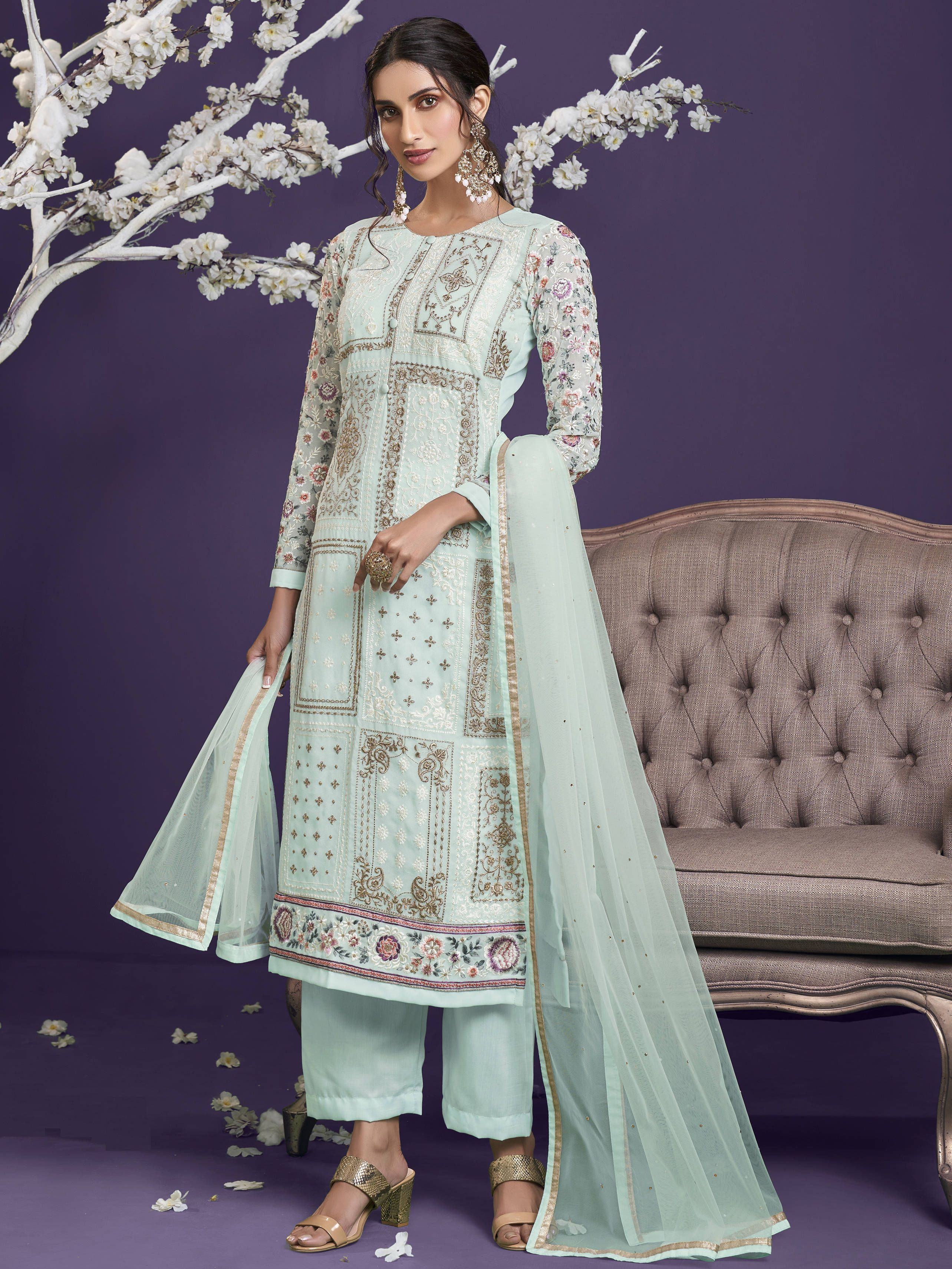 Woman in pastel blue embroidered salwar kameez with dupatta, floral details, and festive jewelry