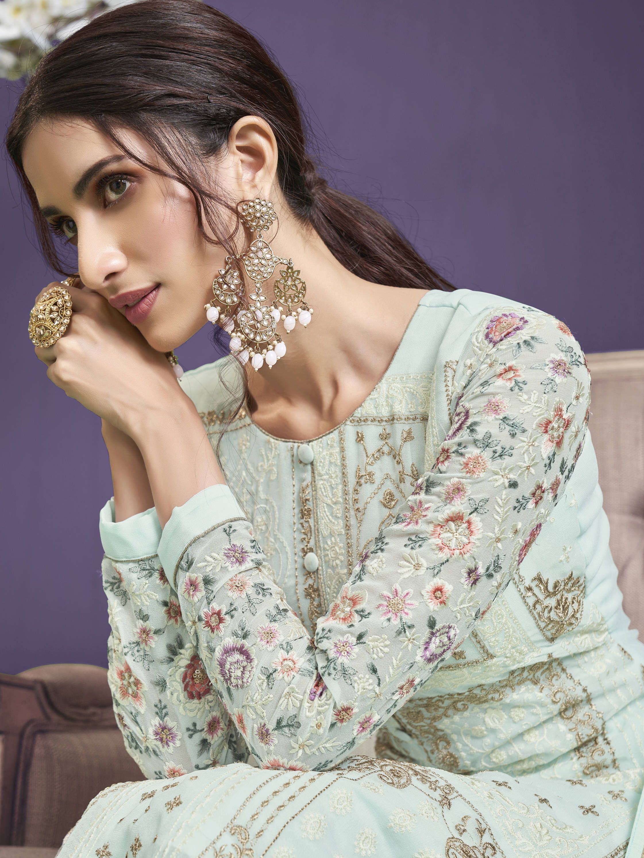 Woman in pastel embroidered ethnic gown with floral details and statement earrings