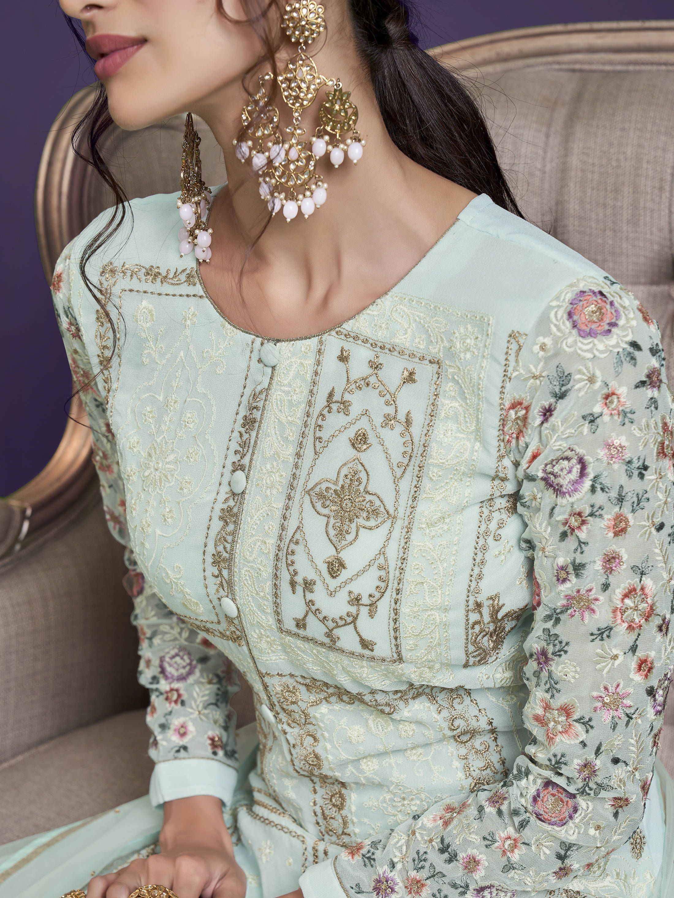 Woman in pastel embroidered salwar kameez with floral long sleeves and statement earrings