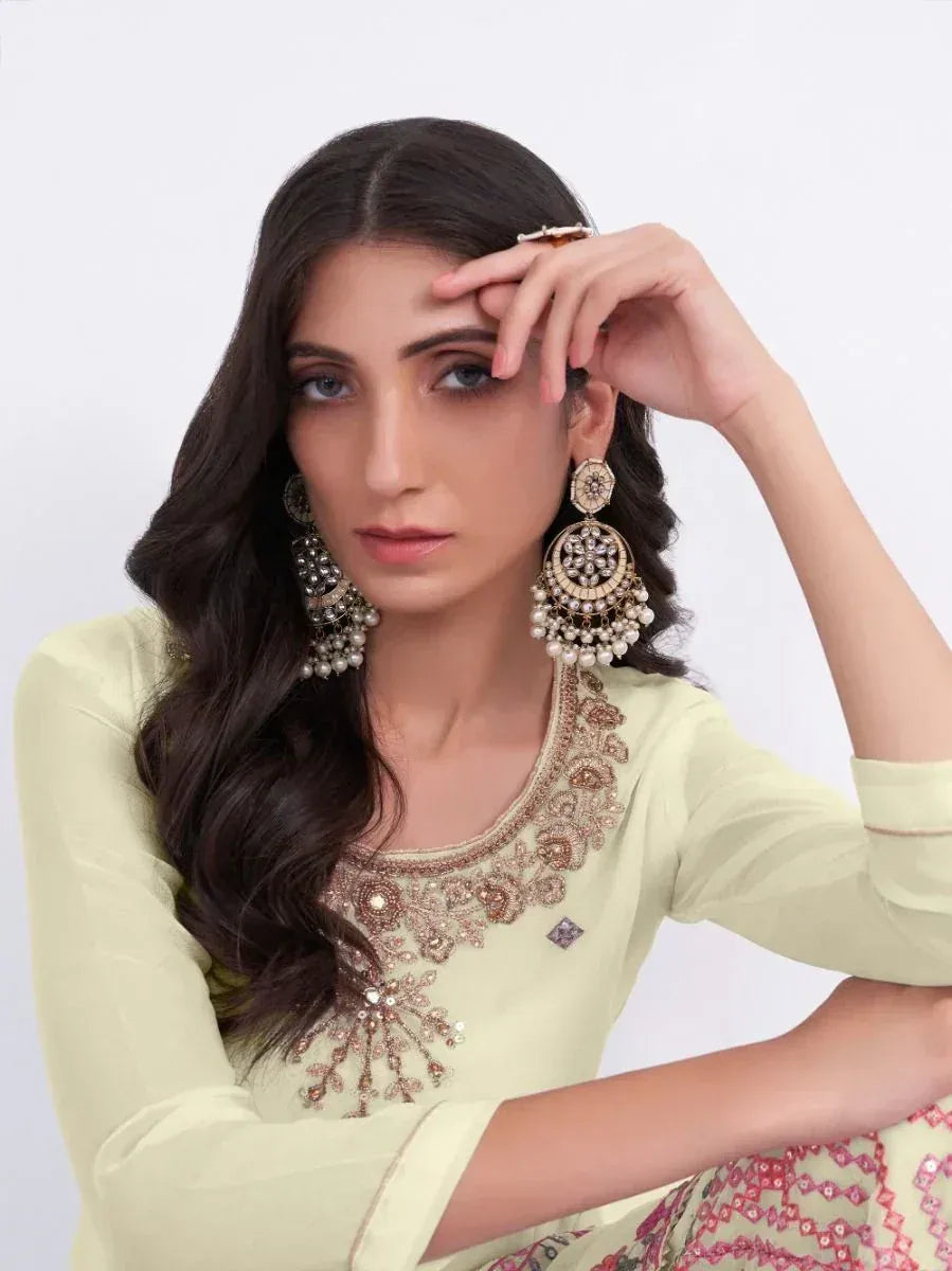 Woman in light green embroidered ethnic top with pearl jhumka earrings, showcasing Indian designer wear