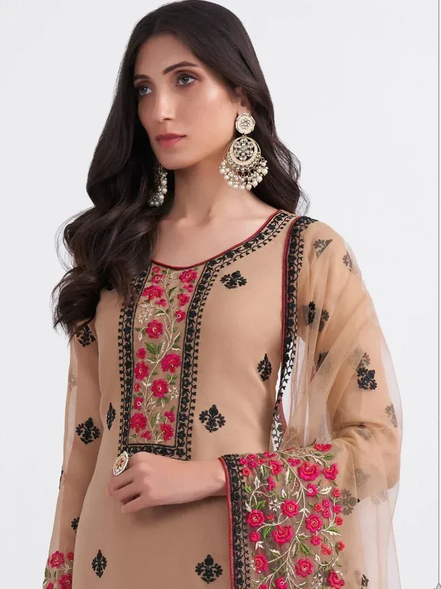 Beige embroidered salwar kameez with pink floral work and black detailing, paired with statement earrings.