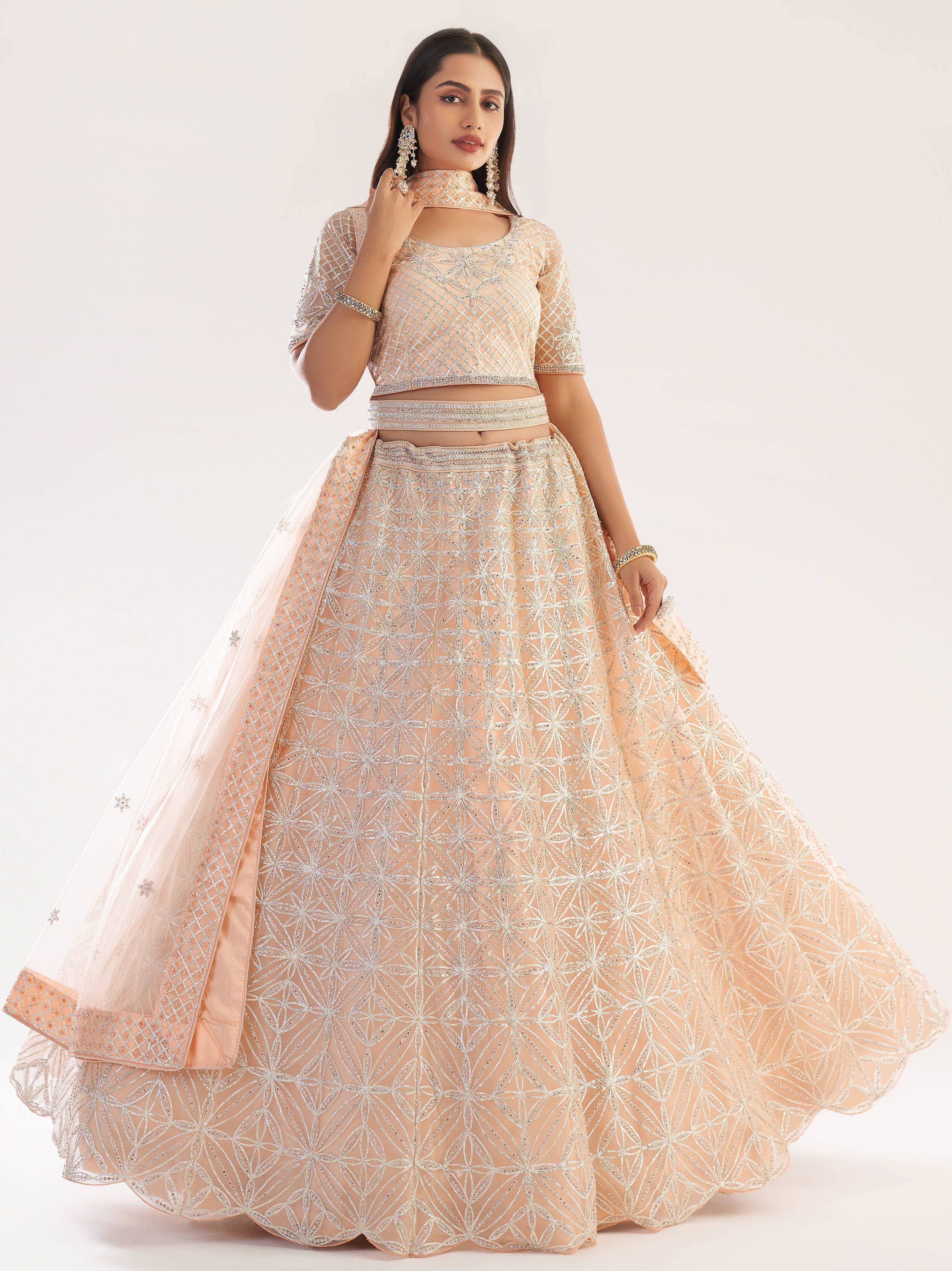 Elegant peach lehenga choli with intricate silver embroidery and sheer dupatta, perfect for Indian weddings and festive occasions.