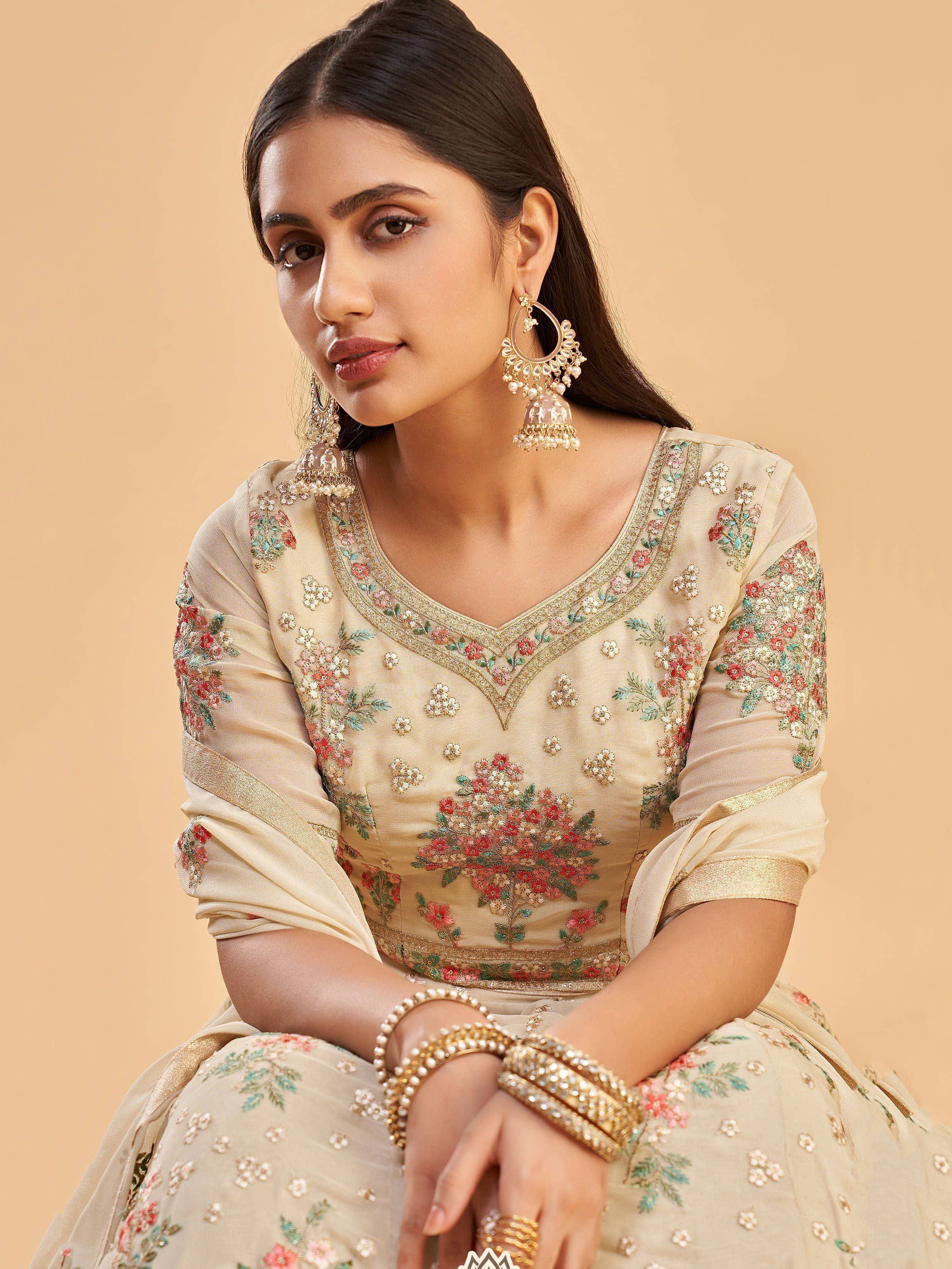 Beige floral embroidered lehenga choli with gold detailing and jhumka earrings