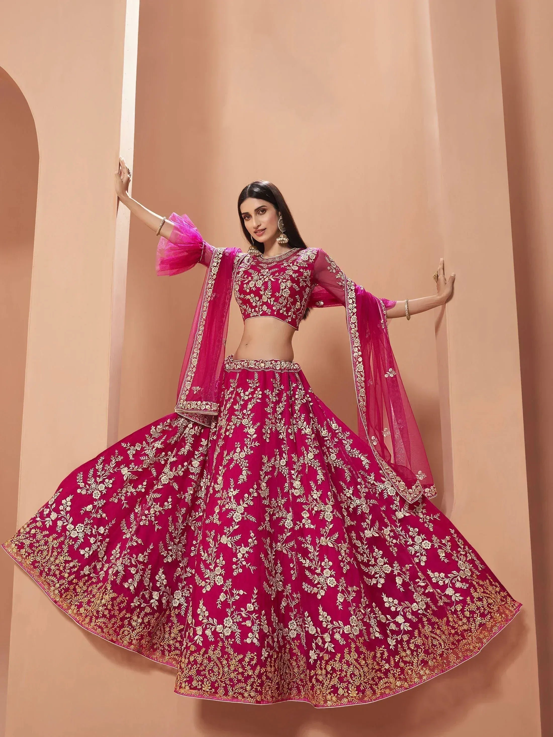 Fuchsia pink embroidered lehenga choli with gold floral work, sheer sleeves, and dupatta for Indian ethnic wear