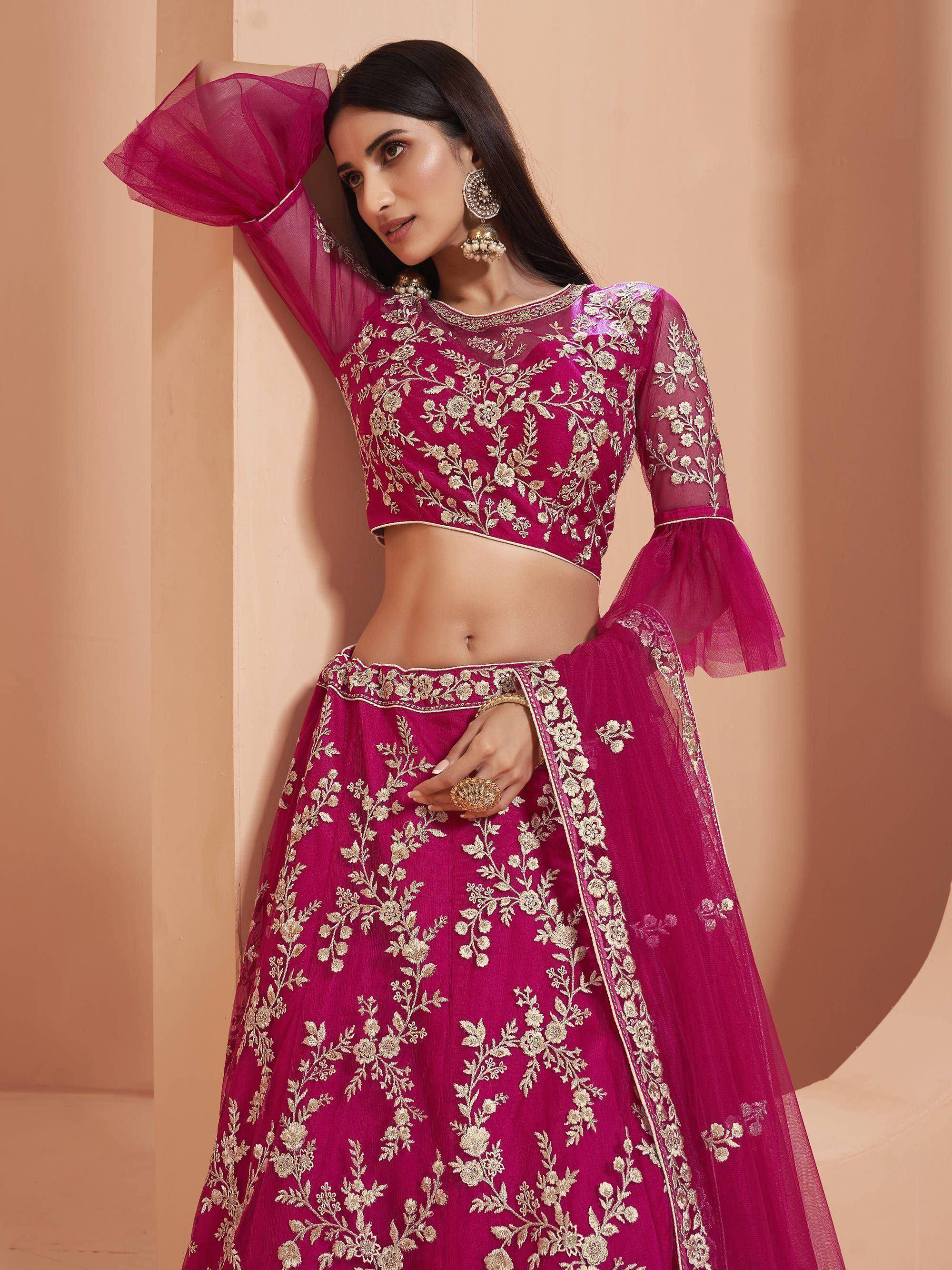Fuchsia embroidered lehenga choli with sheer bell sleeves, gold floral work, perfect for Indian weddings or parties