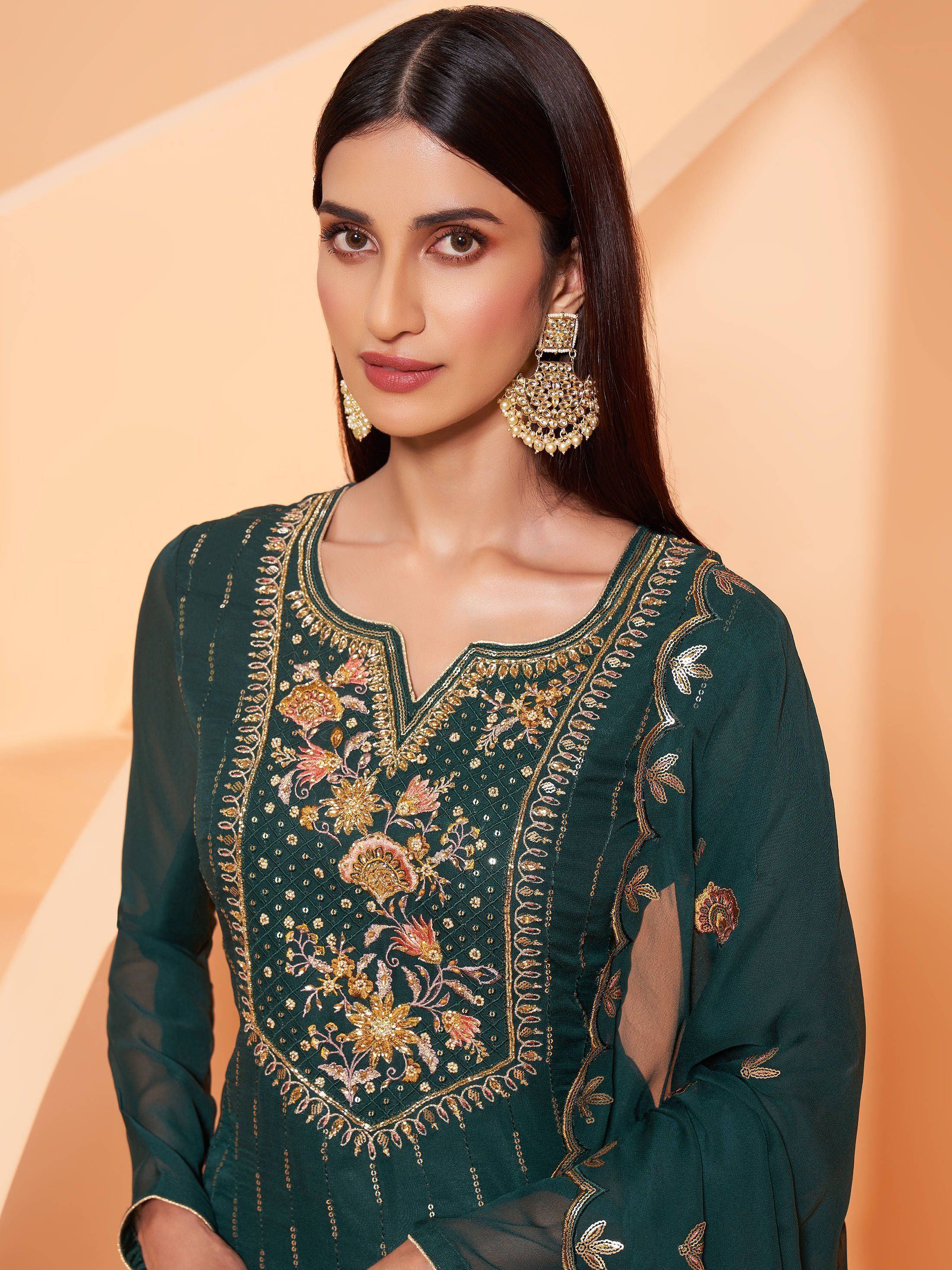 Woman wearing green embroidered salwar kameez with gold floral patterns and statement earrings