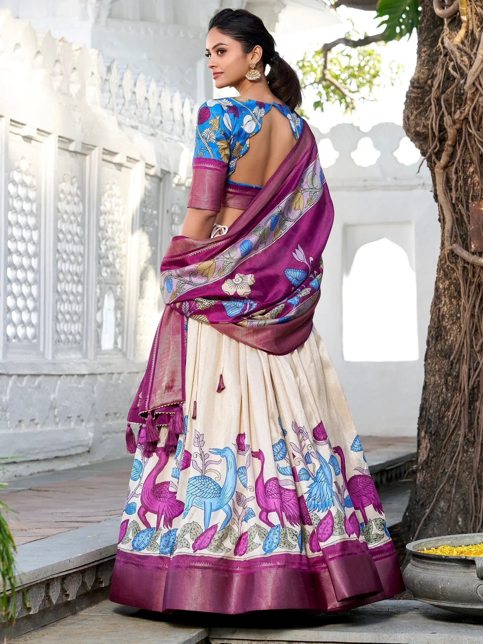 Woman in vibrant purple and blue printed lehenga choli with peacock motifs, ideal for Indian ethnic occasions.