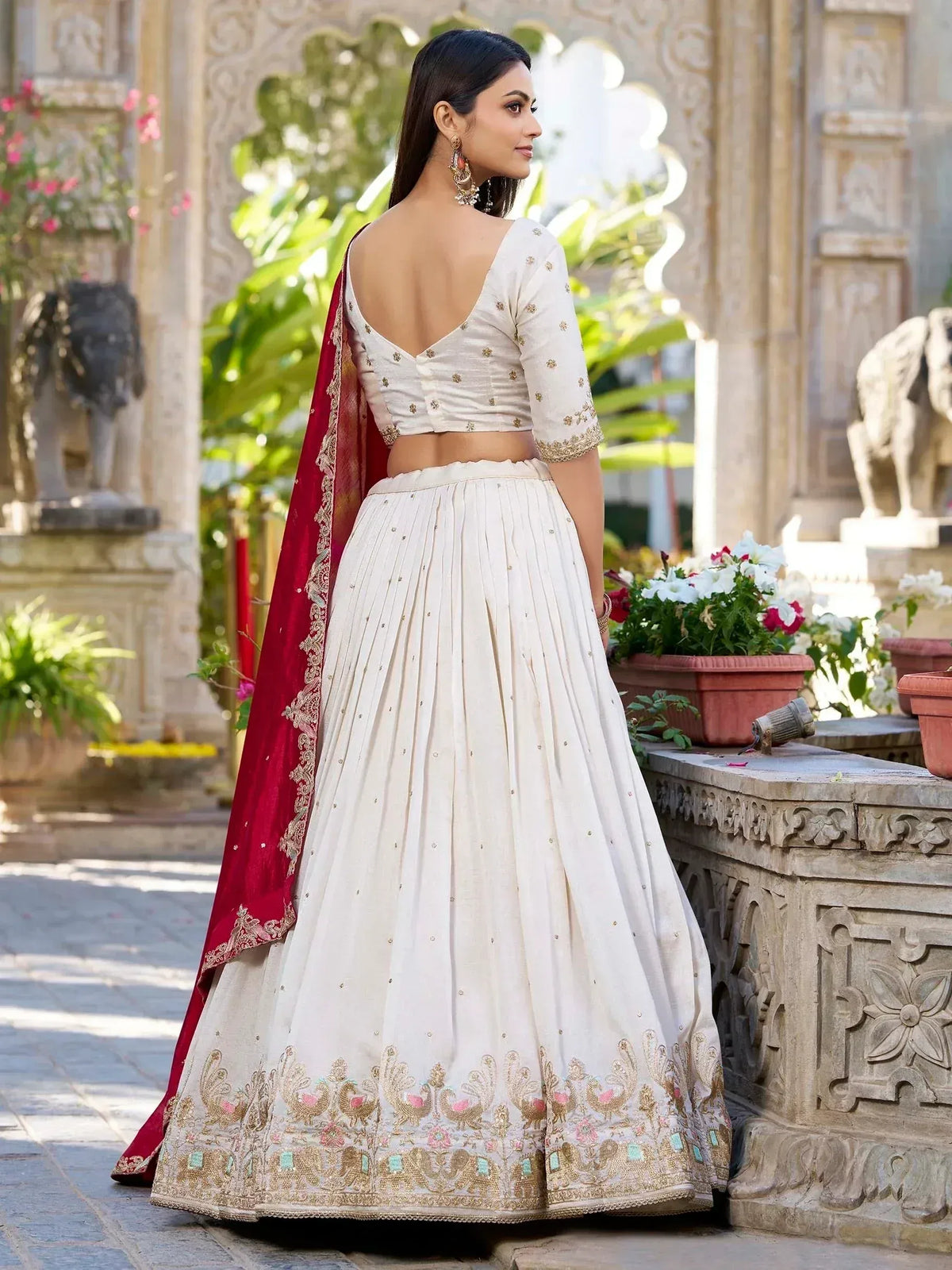 Elegant white lehenga choli with gold embroidery and red dupatta, perfect for Indian weddings and festive occasions.