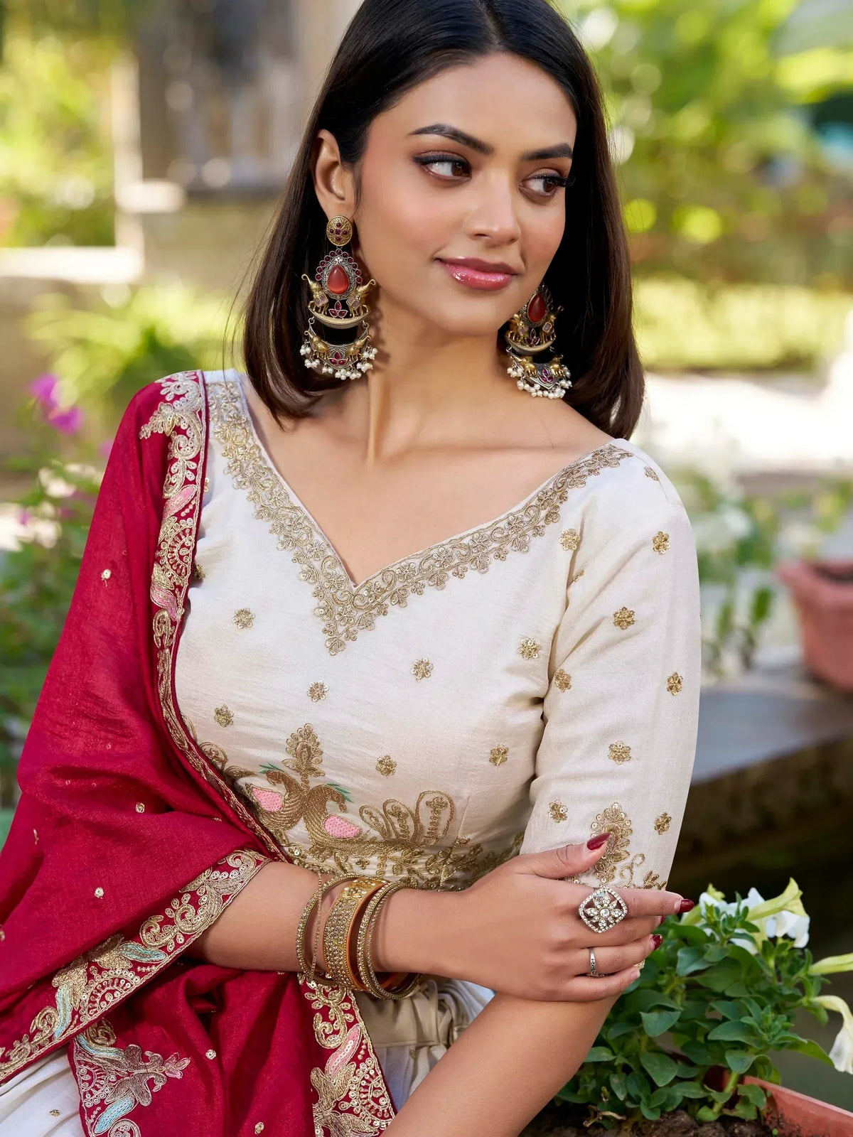 Woman in elegant white and red embroidered salwar kameez with gold detailing and traditional jewelry