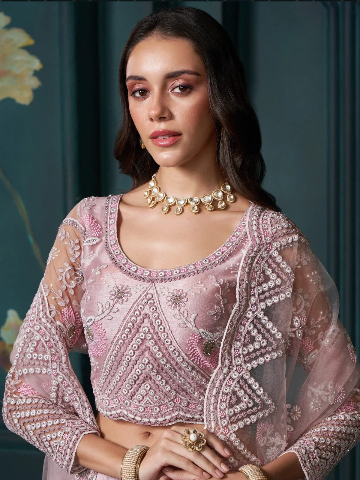 Pink embroidered designer lehenga choli with sheer sleeves and traditional jewelry