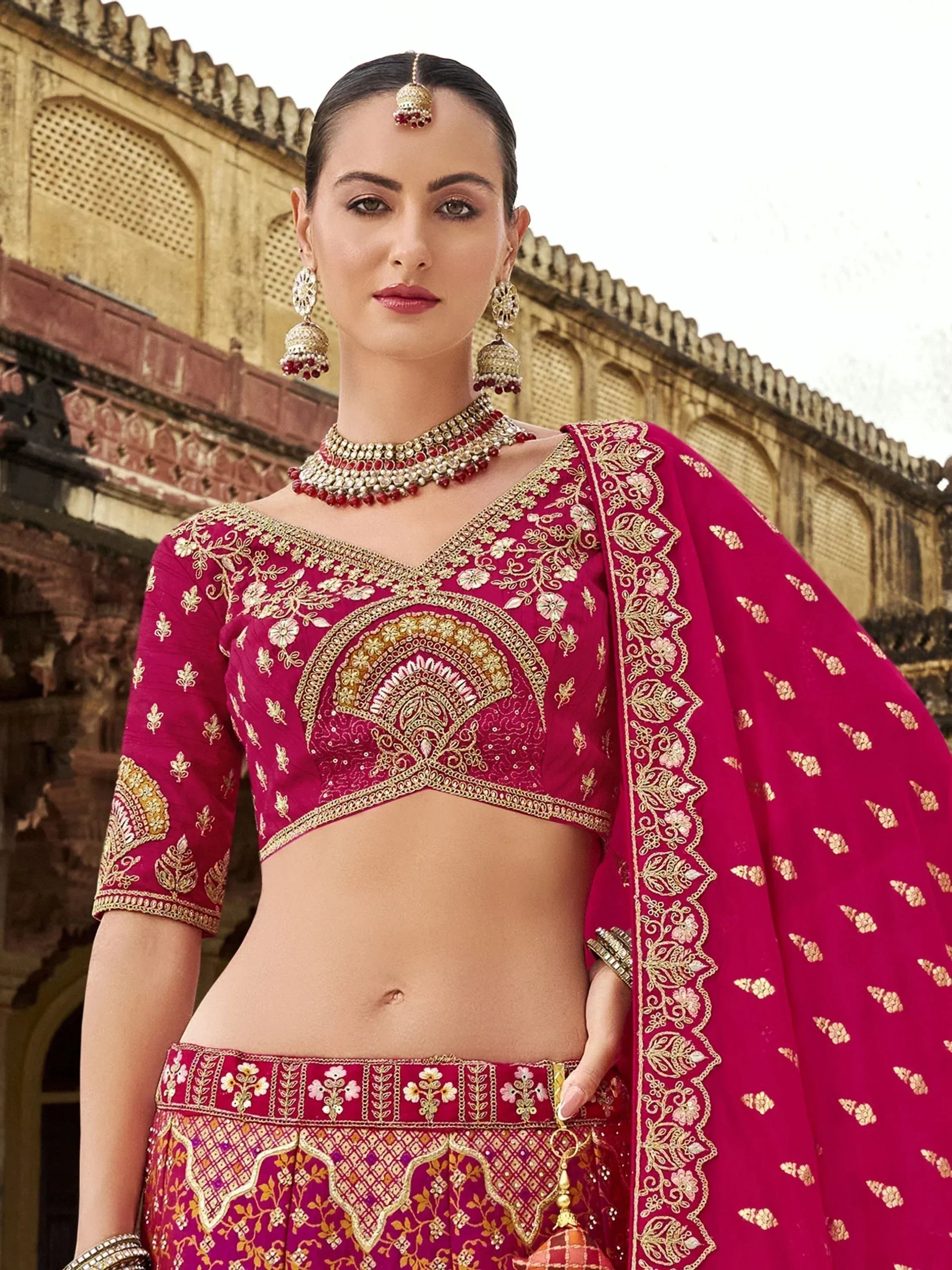 Elegant magenta lehenga choli with gold embroidery, perfect for Indian weddings and festive occasions.