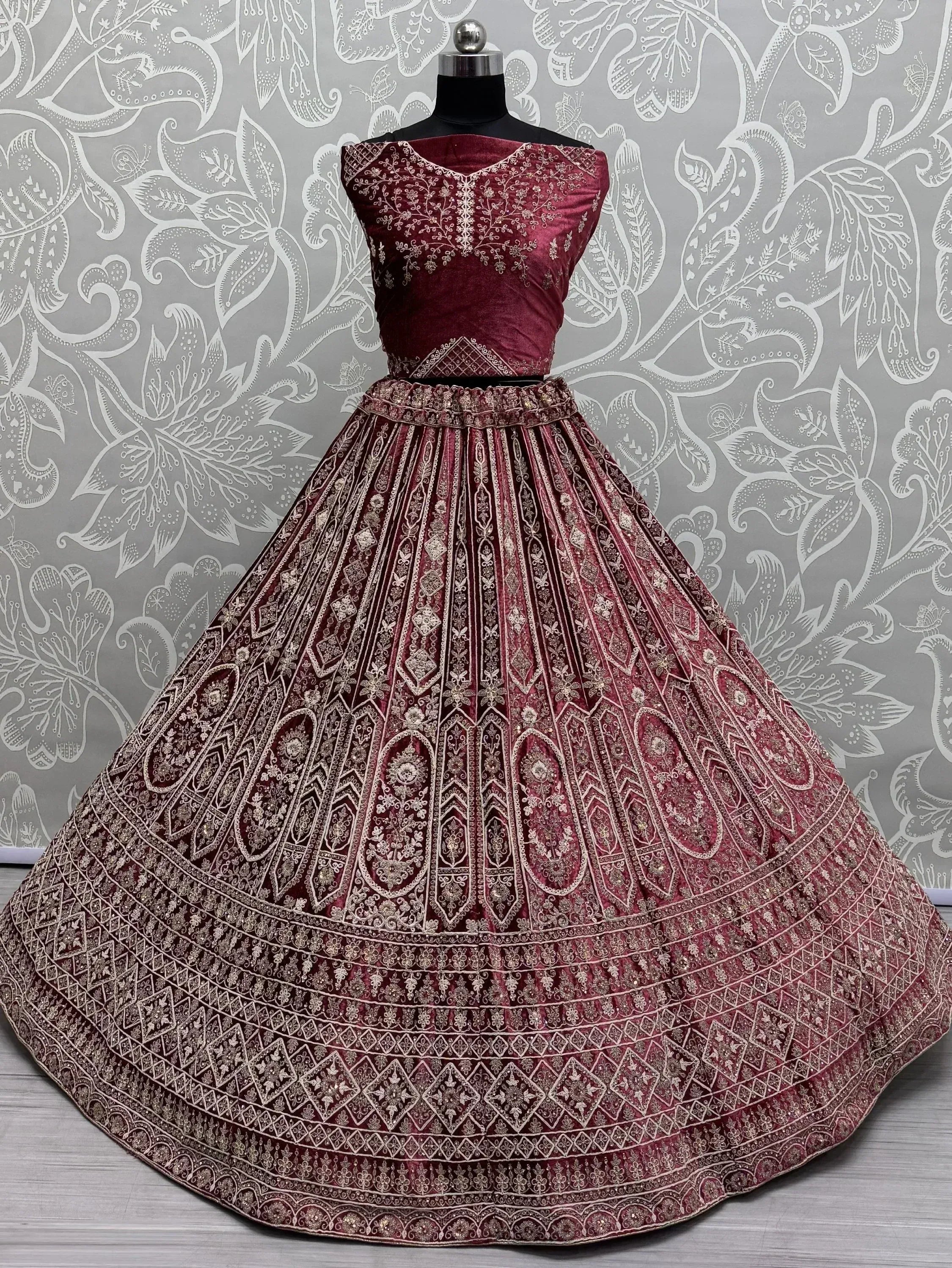 Burgundy velvet lehenga choli with intricate gold embroidery, perfect for Indian weddings and festive occasions.
