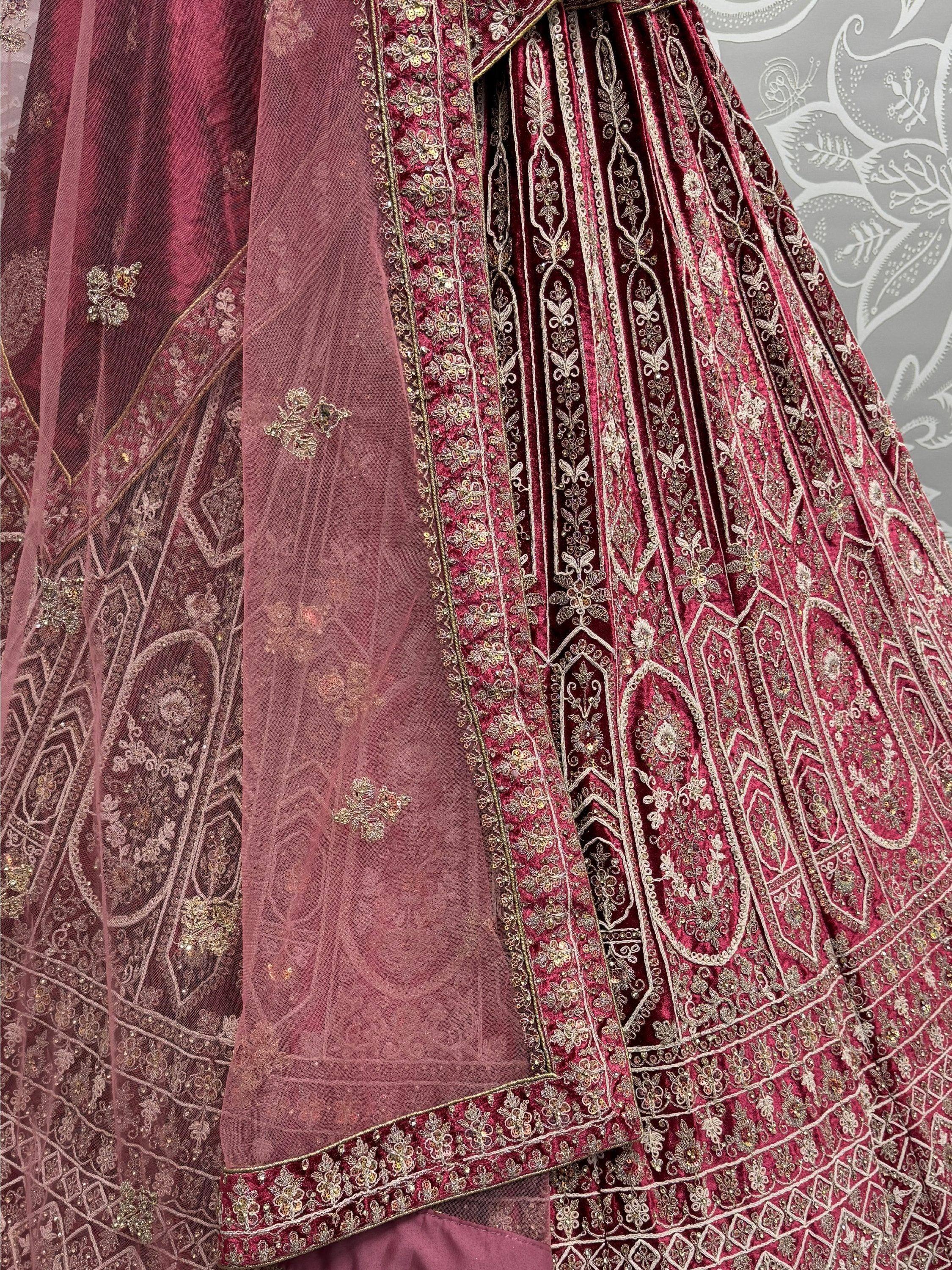 Luxury maroon velvet lehenga with intricate gold embroidery and sheer dupatta, perfect for Indian weddings.