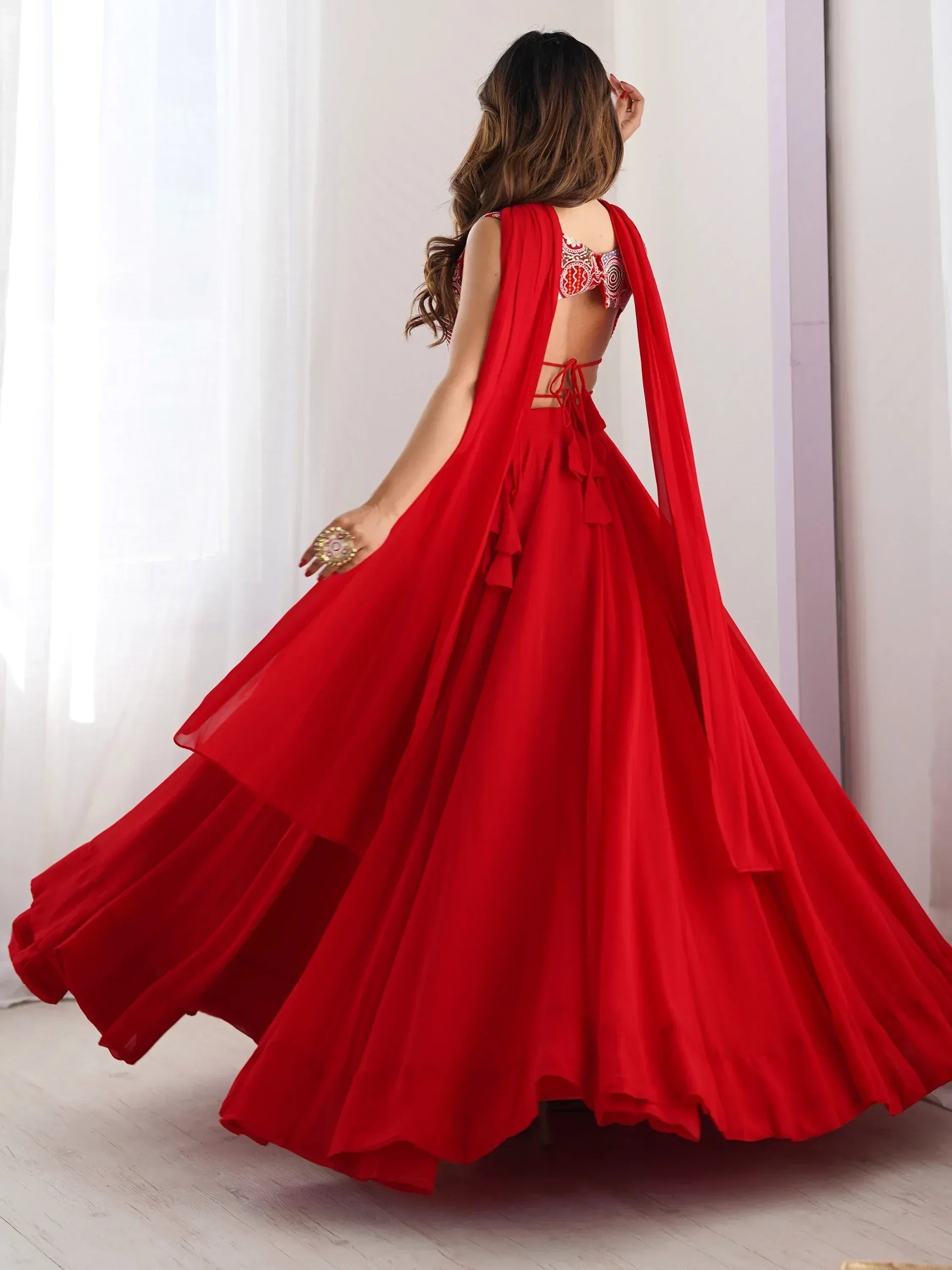 Red designer lehenga choli with backless blouse and flowing skirt, perfect for Indian ethnic wear occasions