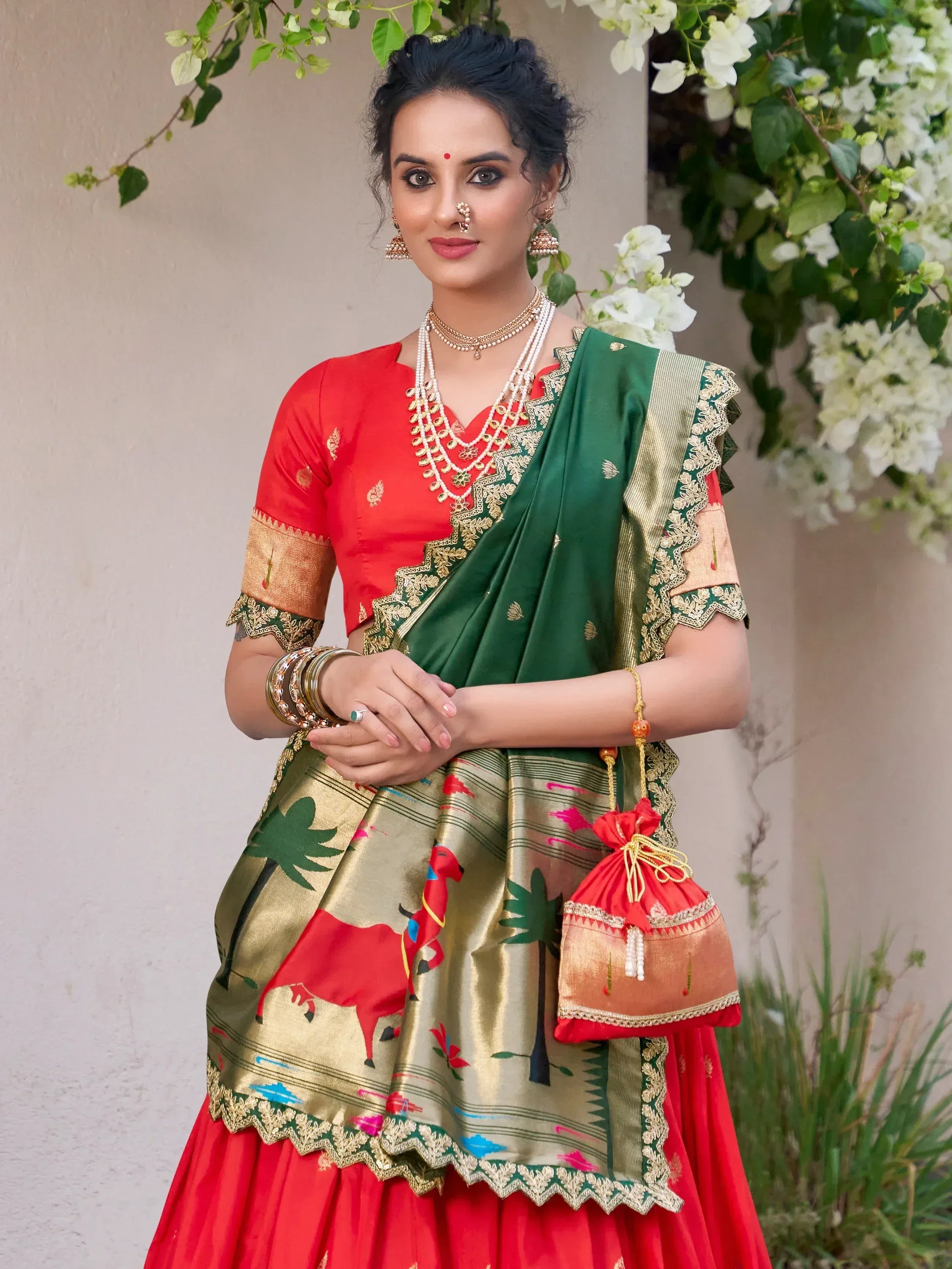 Woman in red and green designer lehenga choli with gold embroidery, floral backdrop