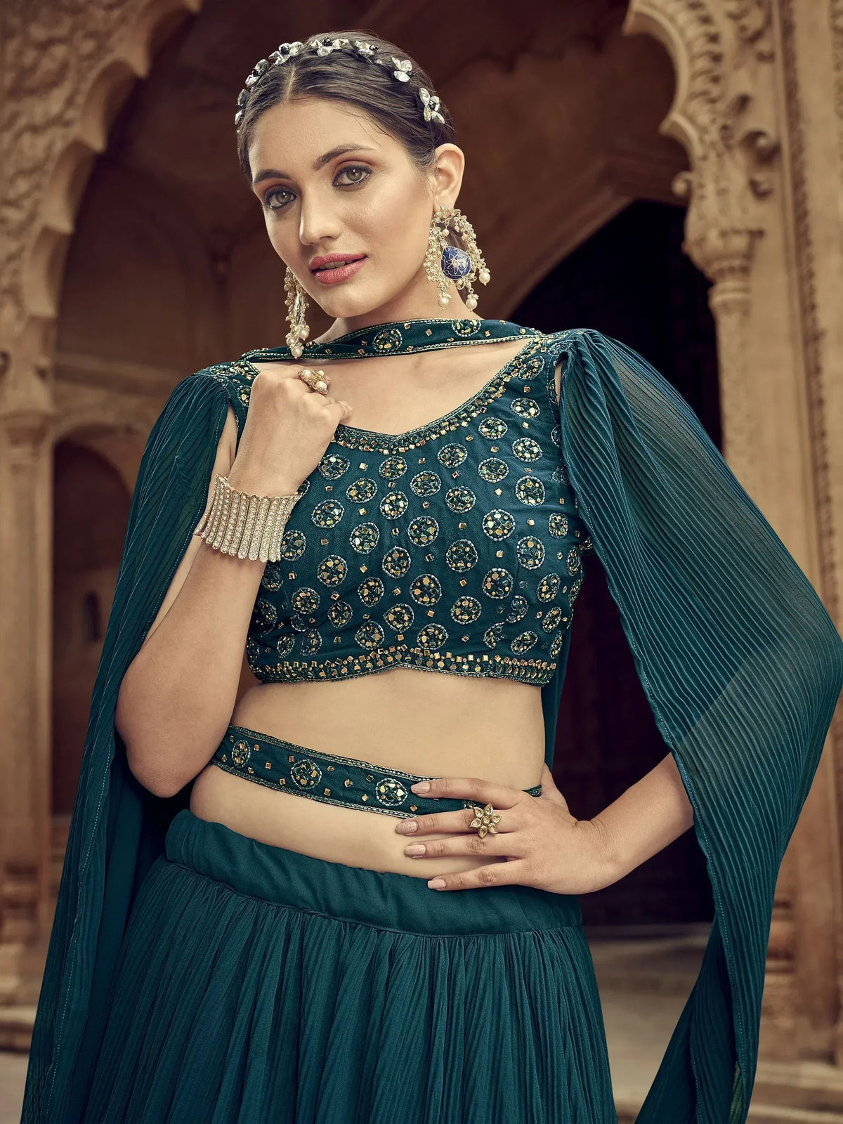 Emerald green designer lehenga choli with mirror work, pleated skirt, and cape sleeves for Indian ethnic wear