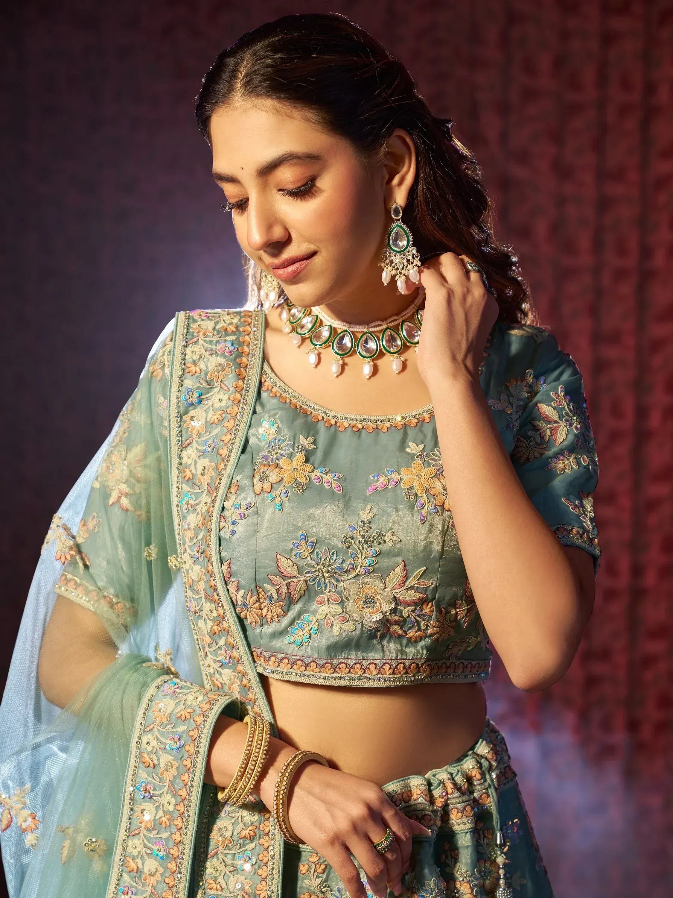 Elegant teal lehenga choli with floral embroidery, paired with traditional jewelry for Indian ethnic wear.