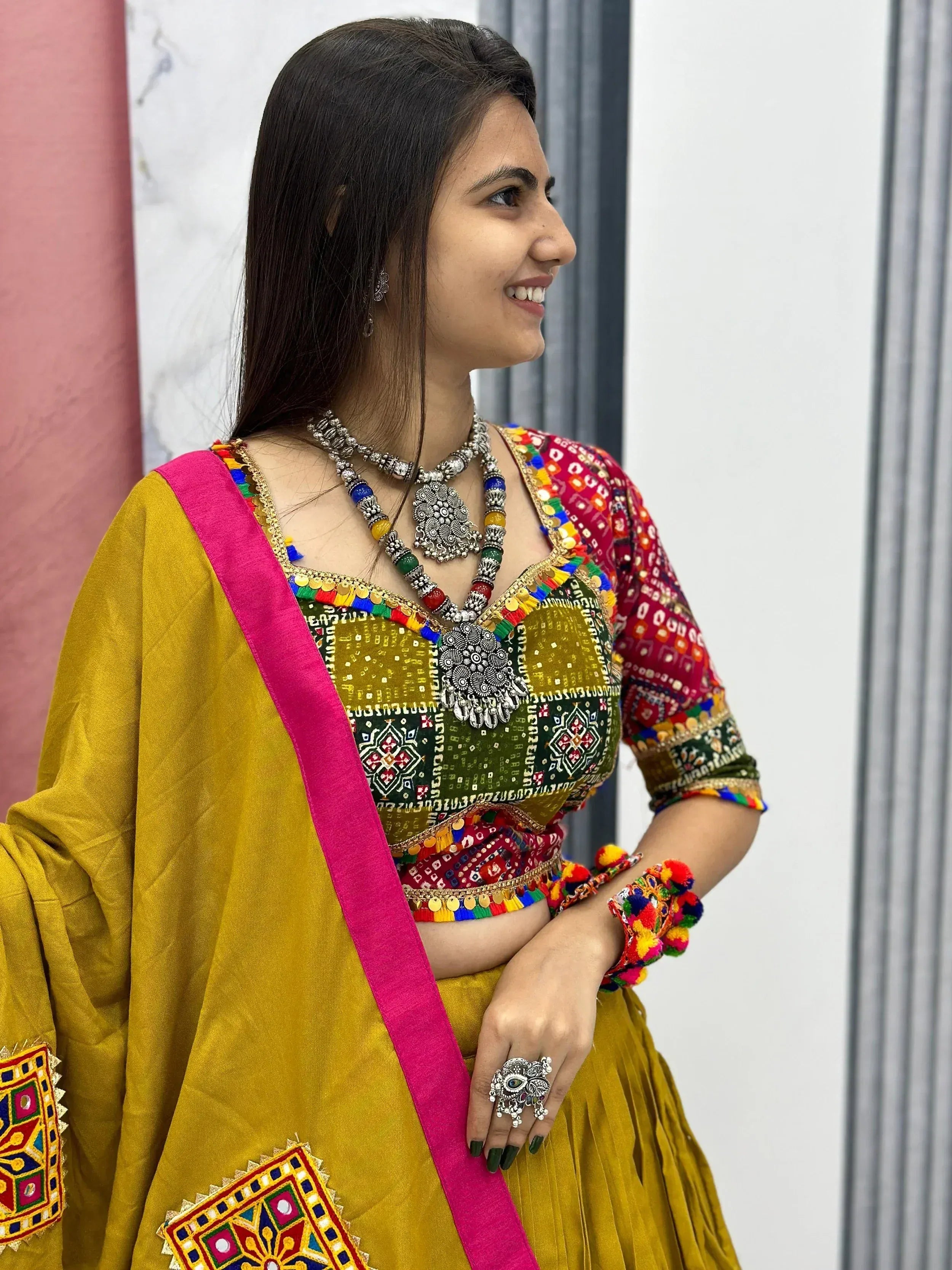 Woman in vibrant yellow and pink embroidered Indian ethnic wear with mirror work and traditional jewelry