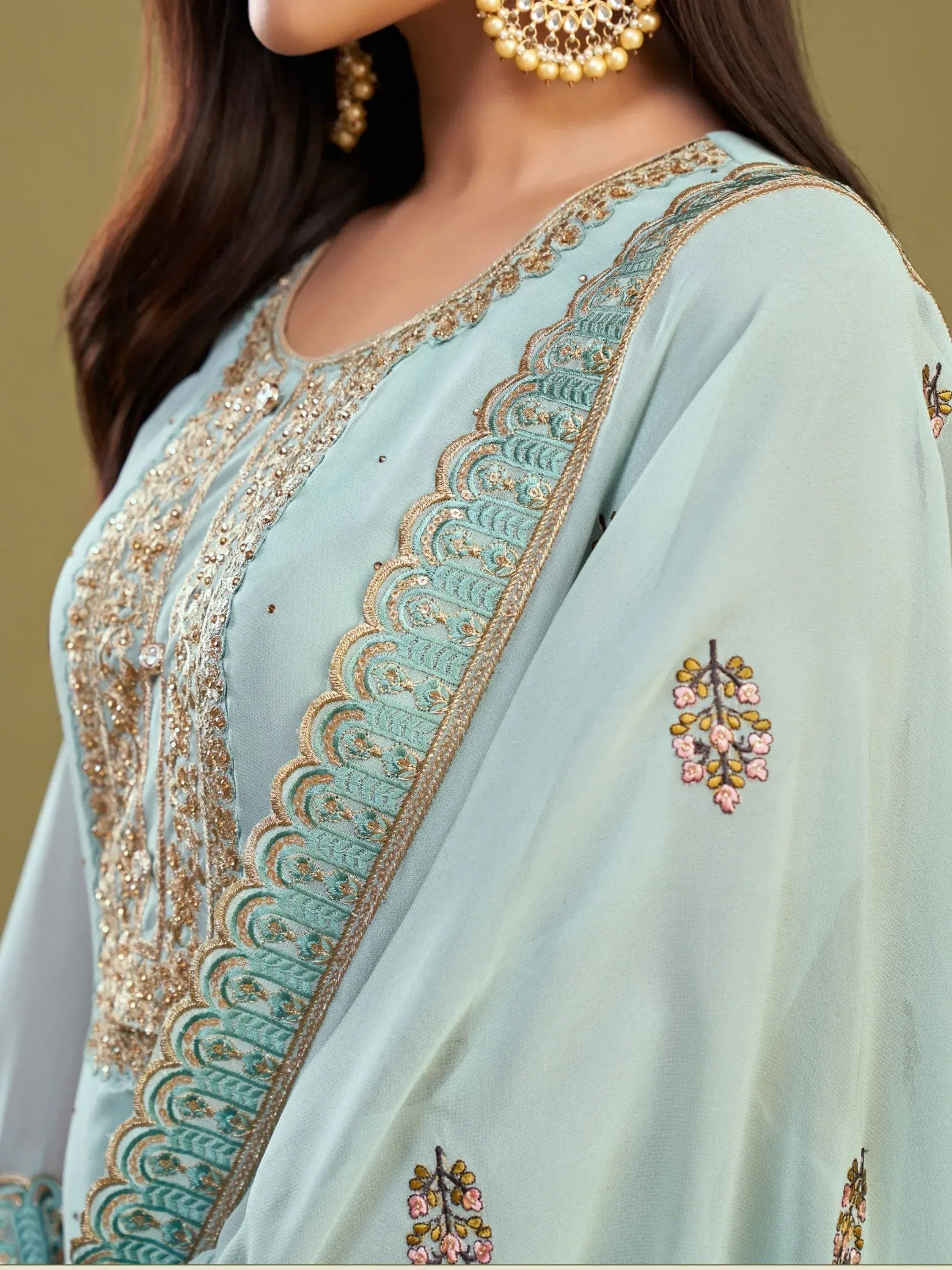 Light blue ethnic salwar kameez with gold embroidery and floral motifs, paired with traditional jewelry